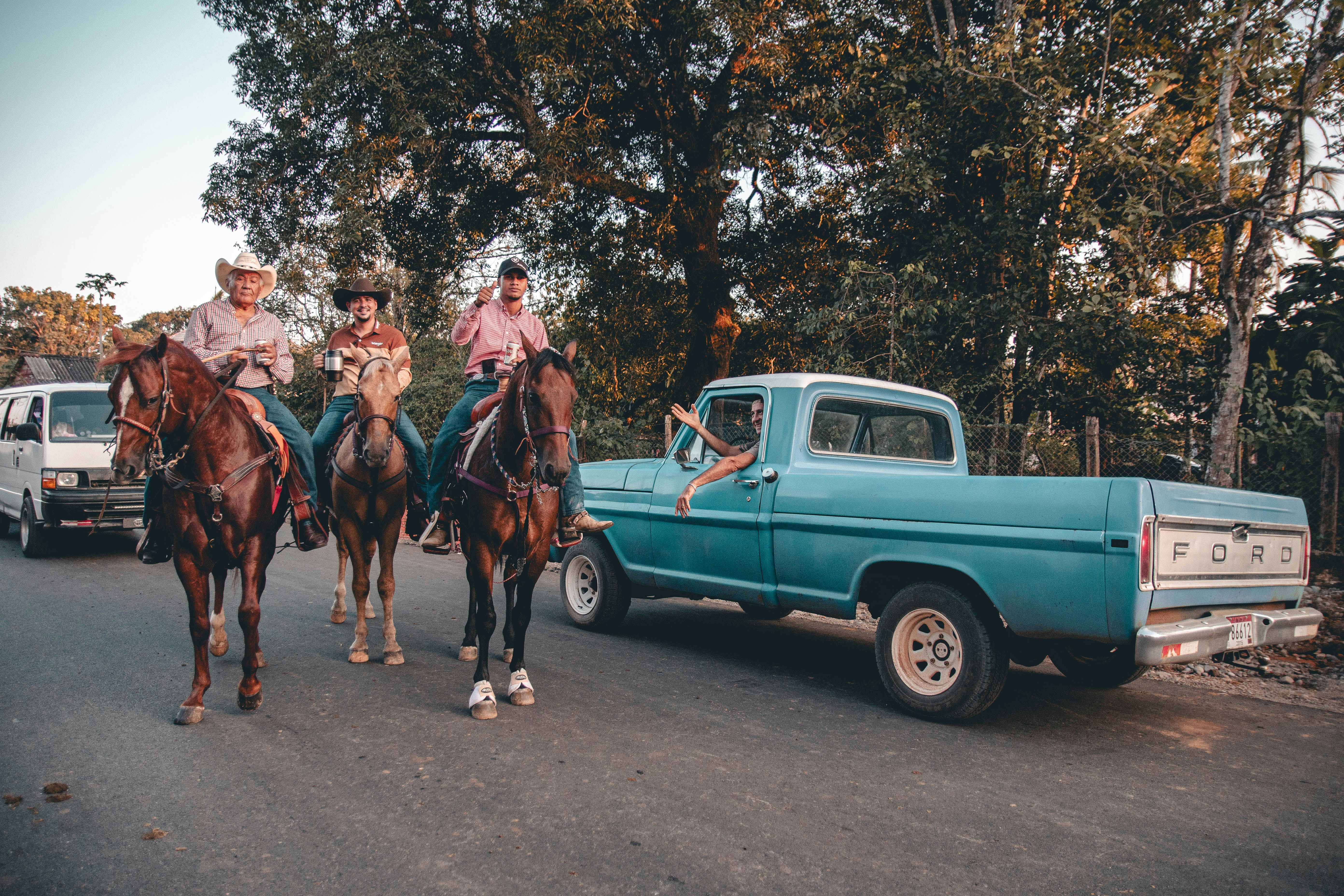 Tres personas a caballo junto a un camión azul antiguo.