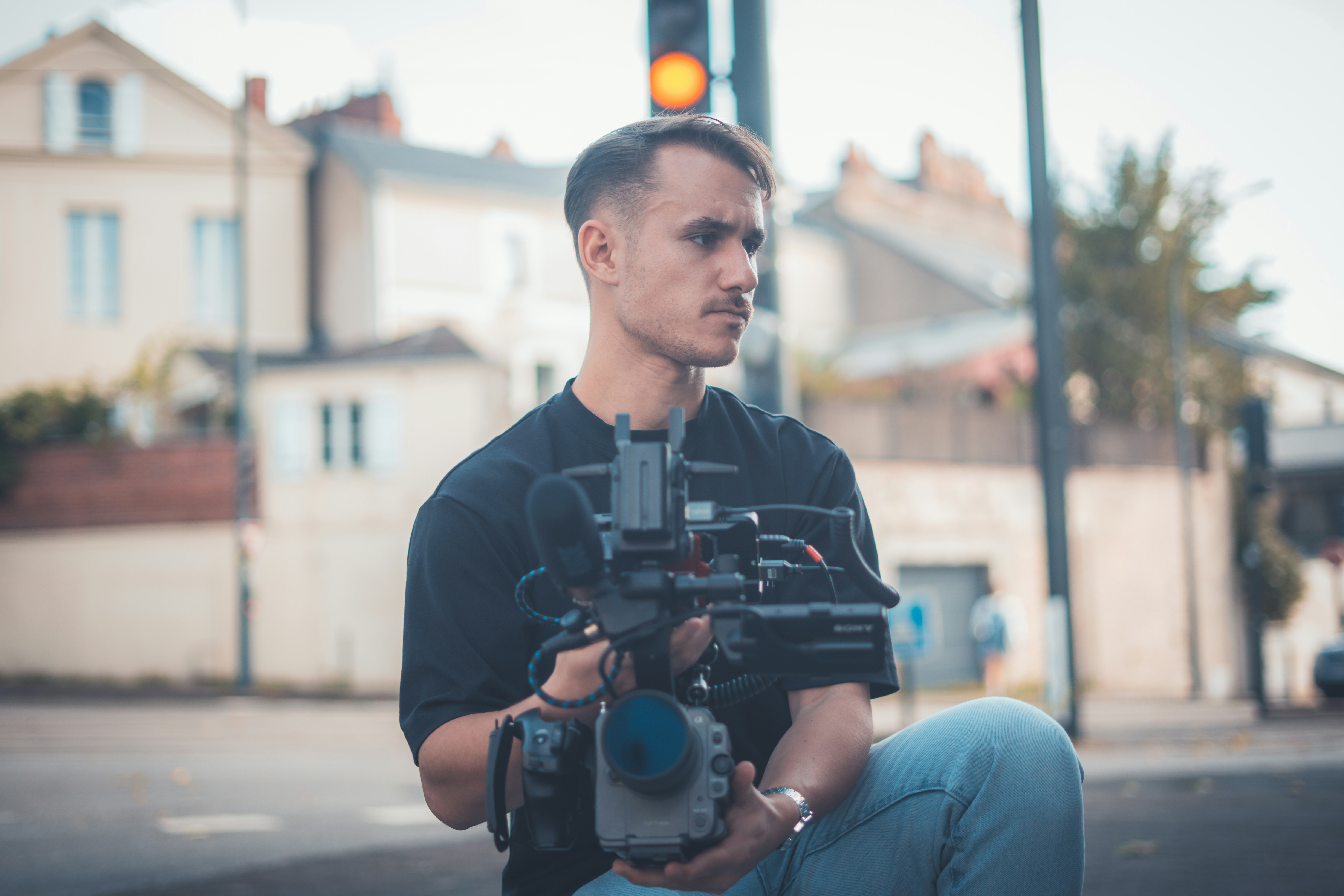 Man holding a professional video camera outdoors.