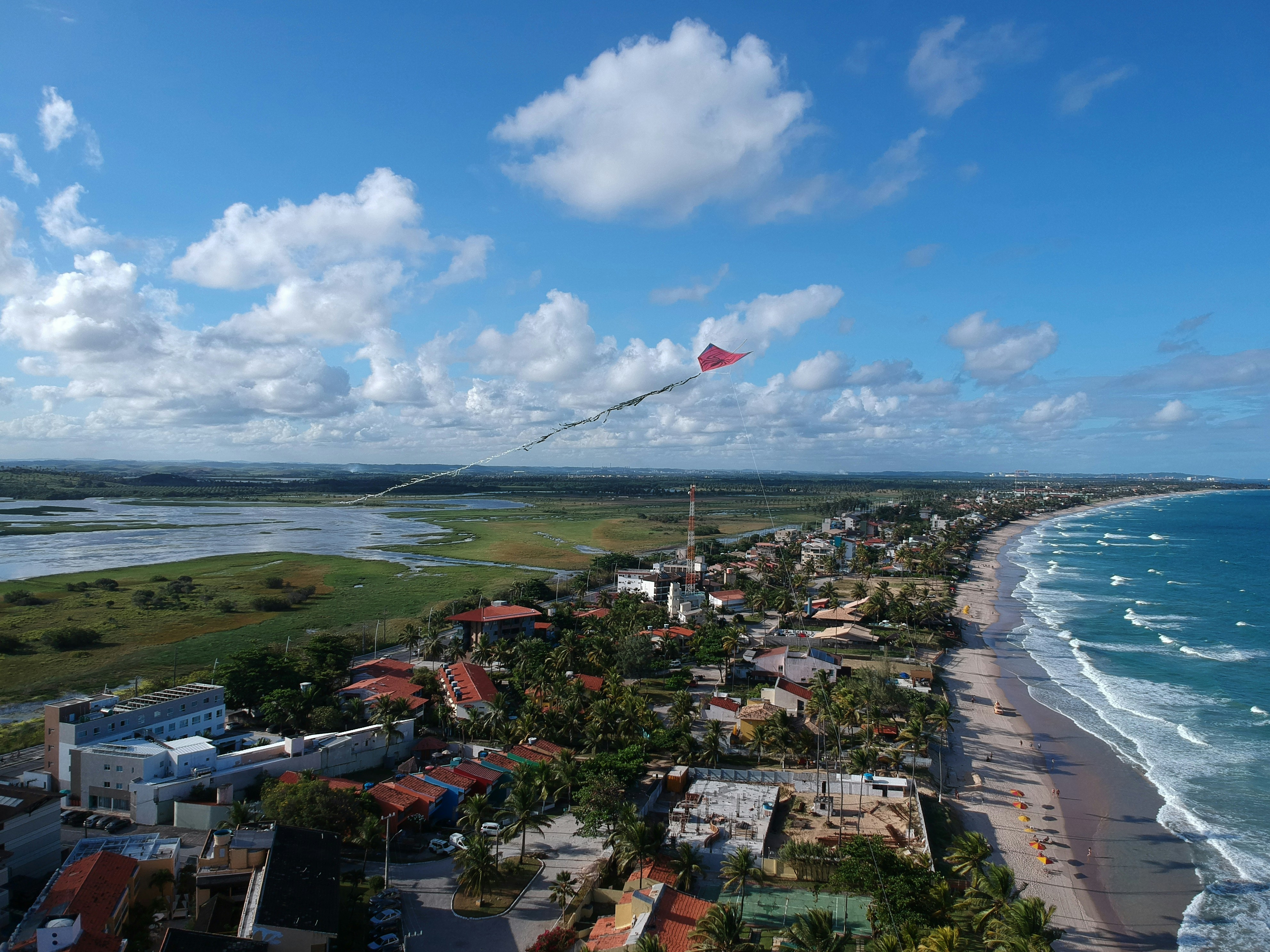 Coastal town with a kite flying over the ocean.