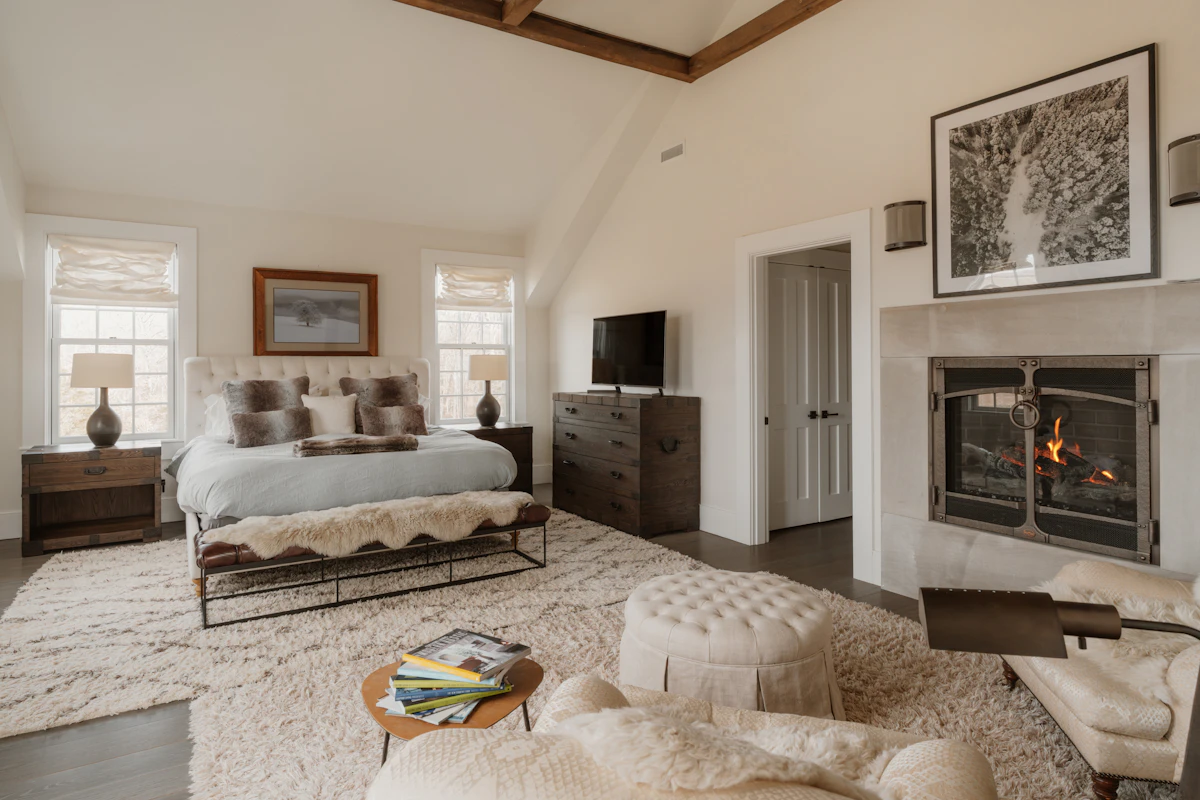 A spacious primary suite with a fireplace, vaulted beamed ceiling, and a seating area