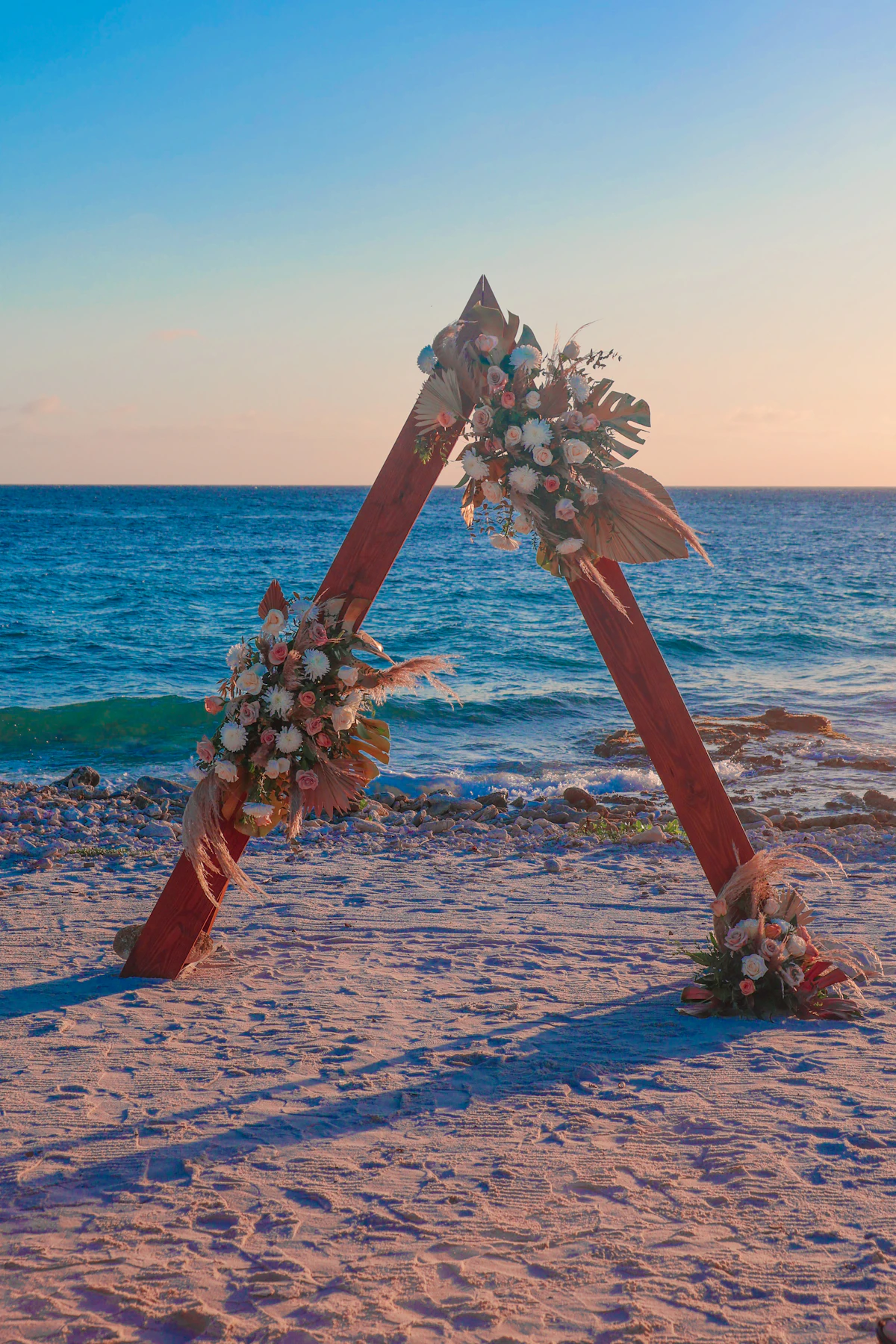 A wooden arch decorated with flowers on a beach