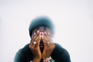 Person covering face with hands, wearing rings.