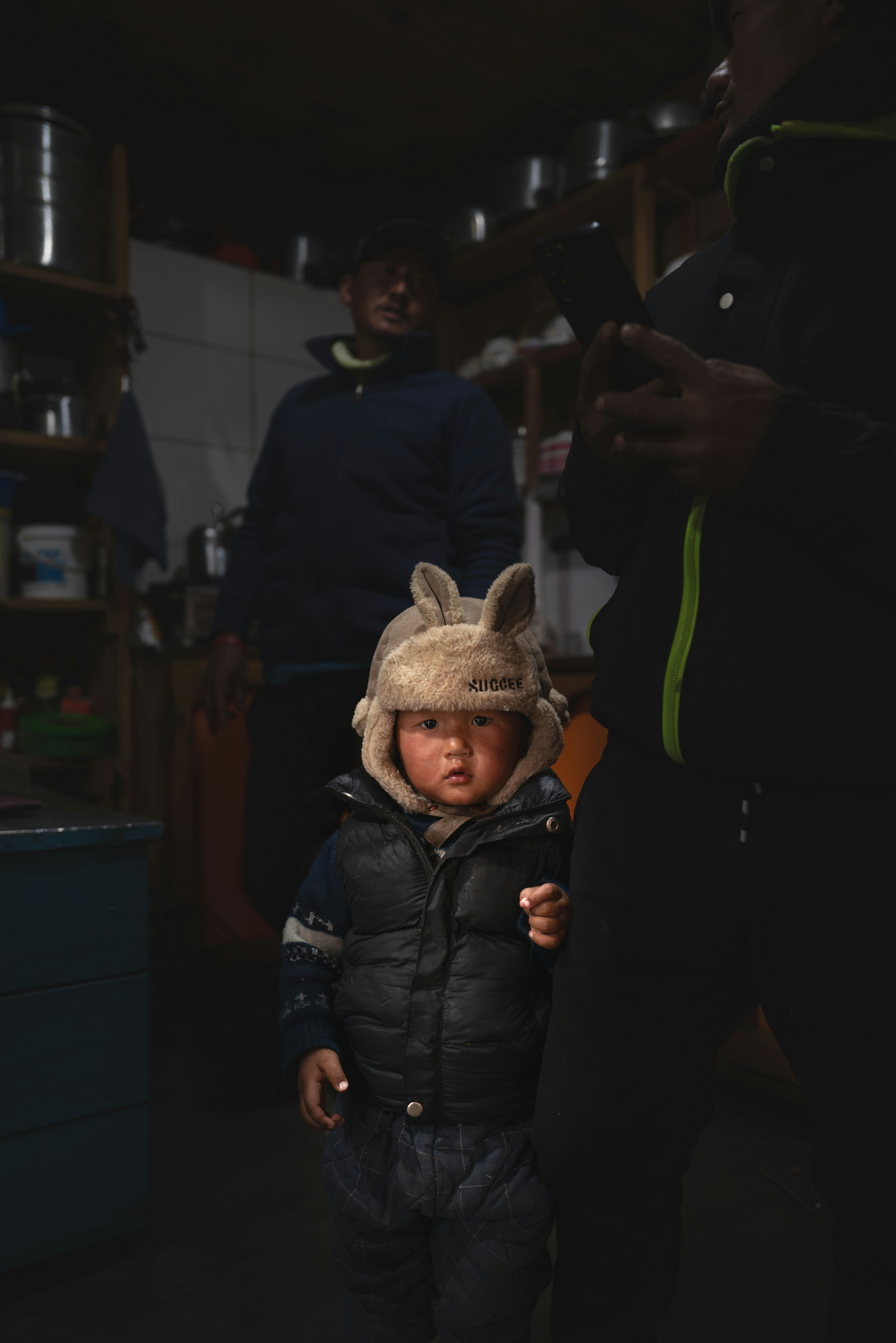 A young child wearing a fuzzy hat and puffer vest.