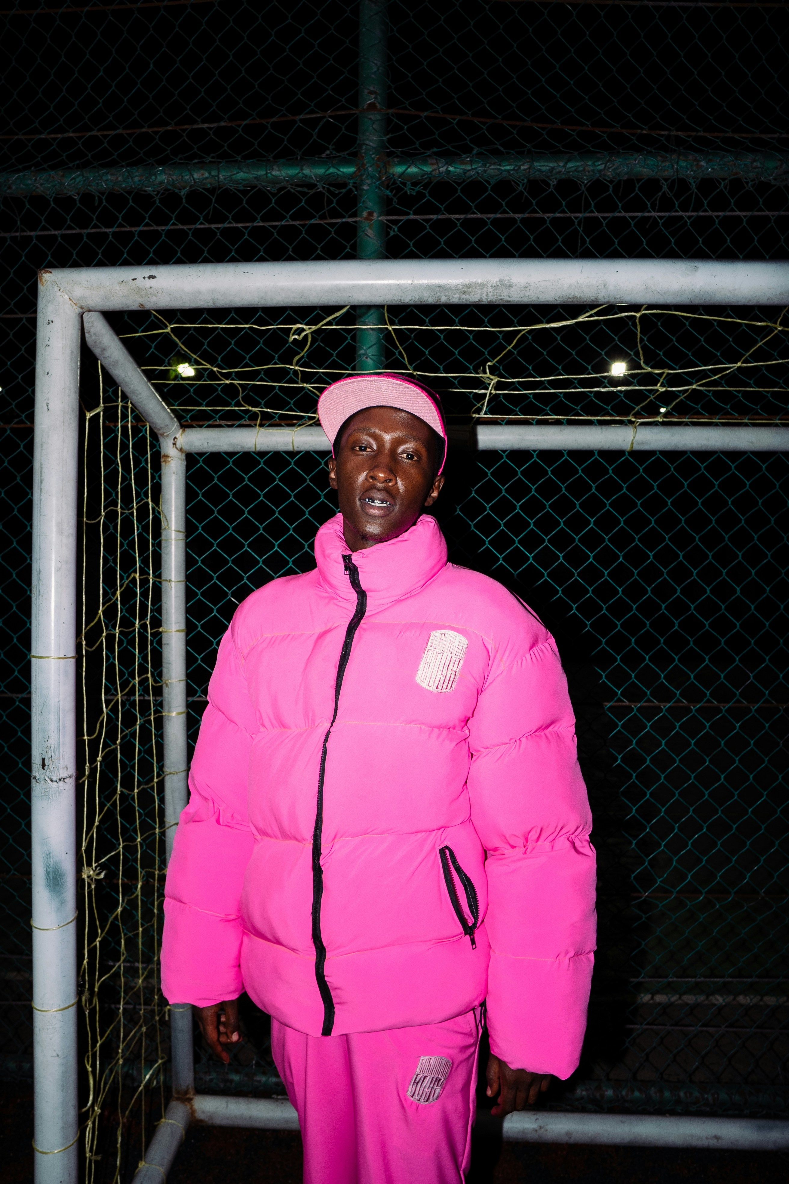 Man in pink puffer jacket and cap on sports field