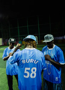 Three men in blue jerseys on a soccer field