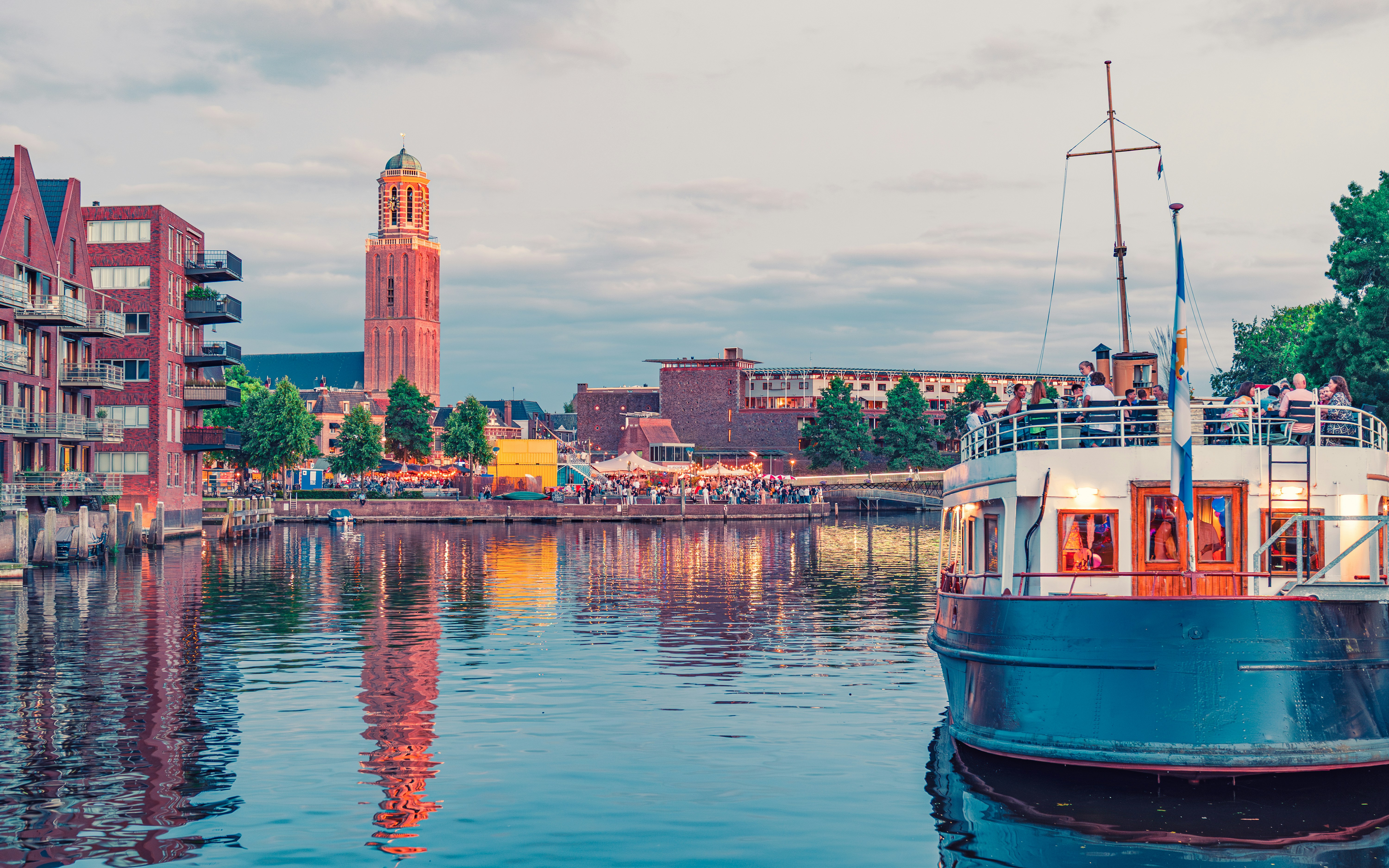 Boat on canal with city buildings and tower.