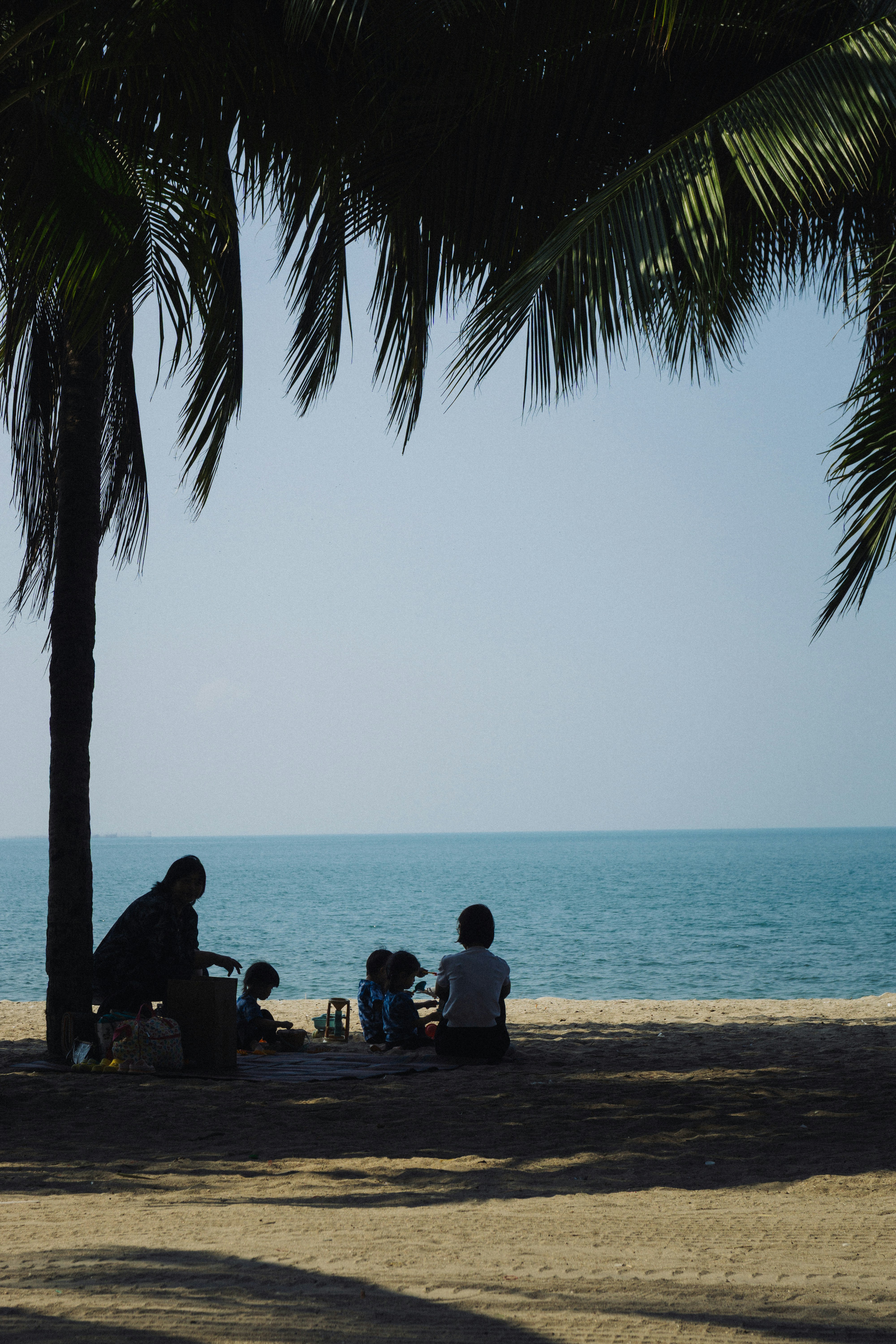 Family relaxing on a sandy beach under palm trees