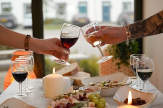 Two hands clinking wine glasses over a table setting