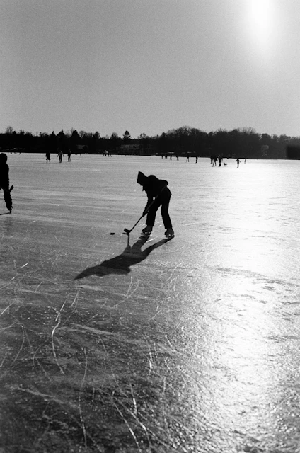People ice skating on a frozen lake in winter.