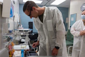 Scientist in lab coat examines sample in laboratory.