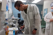 Scientist in lab coat examines sample in laboratory.