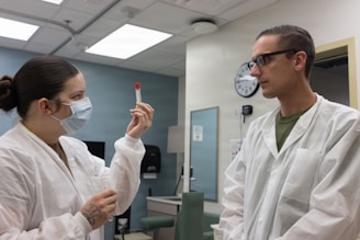 Two medical professionals in lab coats examine a test tube.