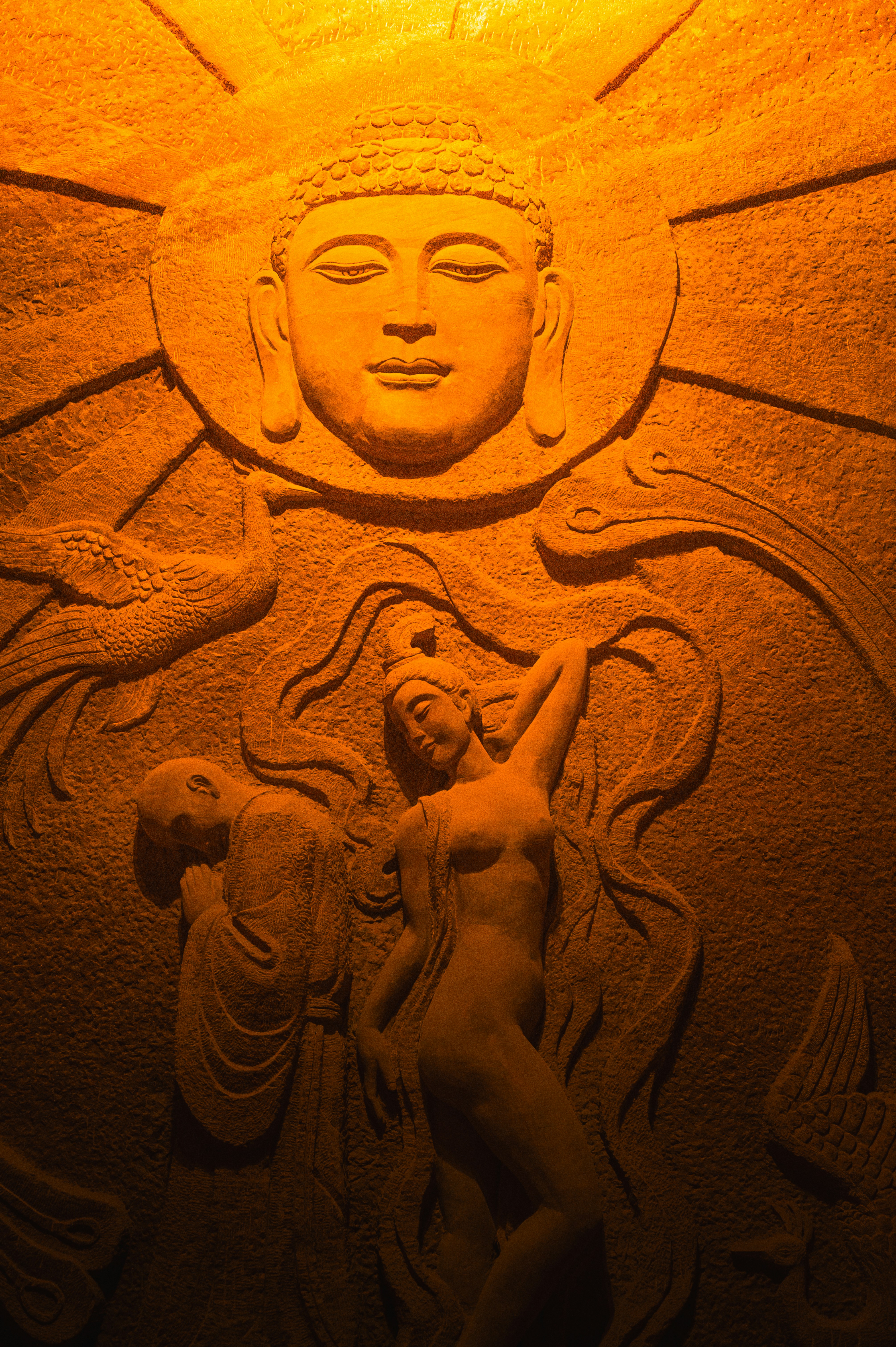 Buddha stone carving with figures and birds