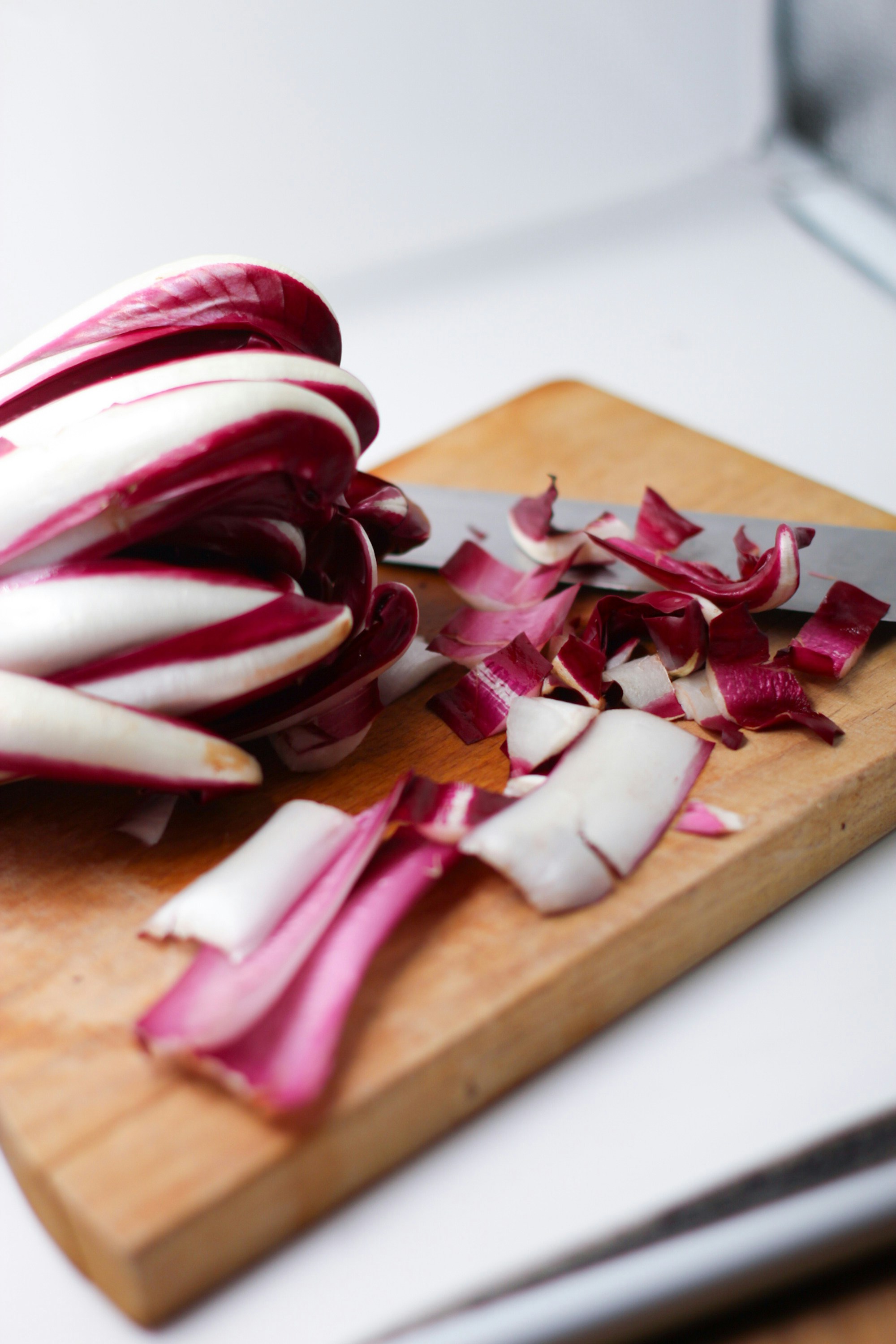 Hojas de radicchio siendo cortadas en una tabla de cortar de madera