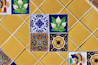 Colorful decorative tiles arranged on a yellow tiled wall