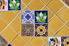 Colorful decorative tiles arranged on a yellow tiled wall
