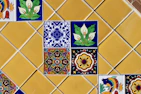 Colorful decorative tiles arranged on a yellow tiled wall