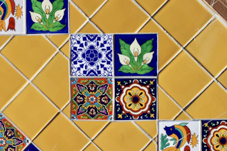 Colorful decorative tiles arranged on a yellow tiled wall