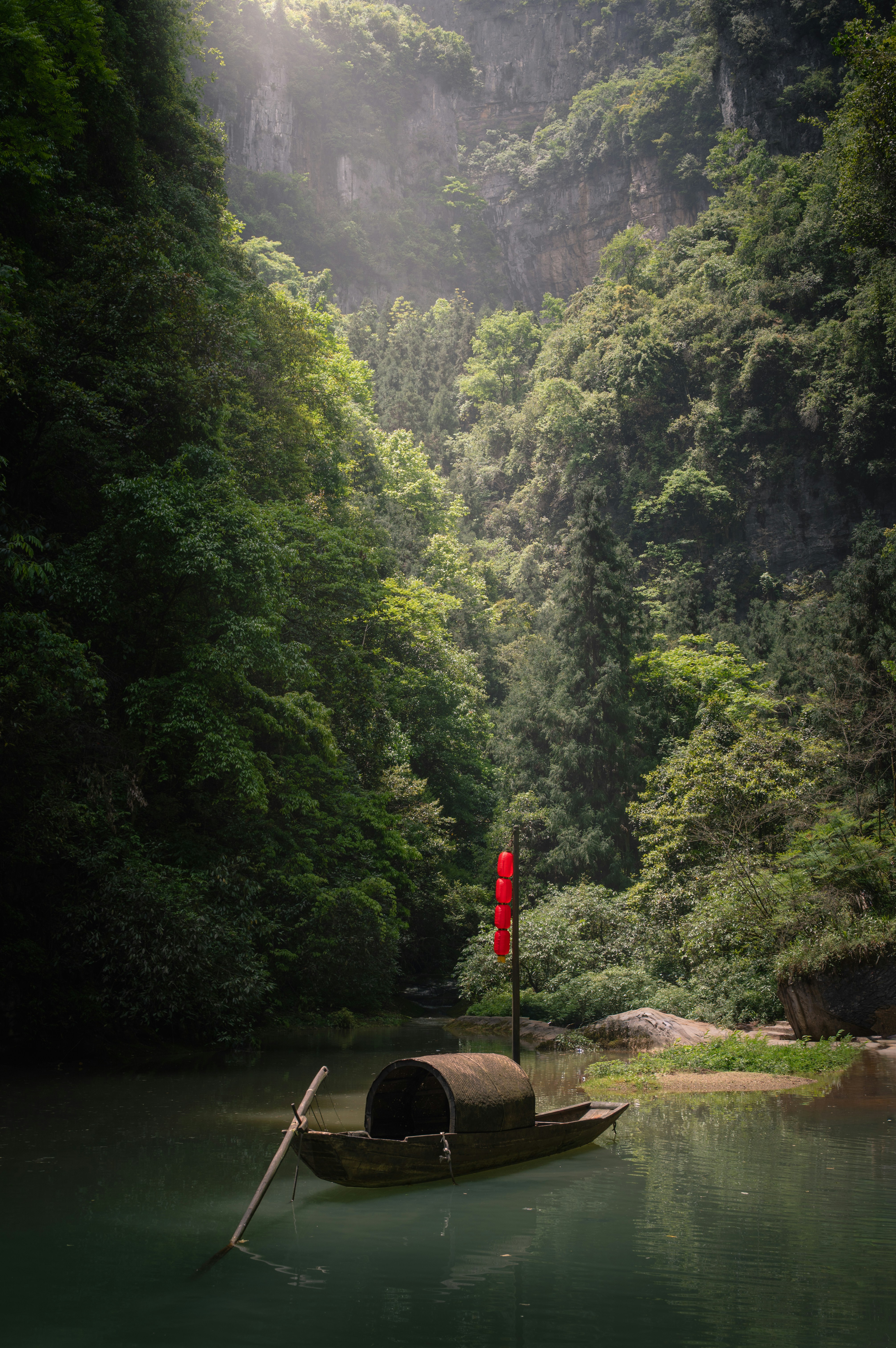 A small boat with a red lantern on a river.