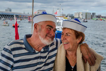 Couple in sailor hats on a boat with city background