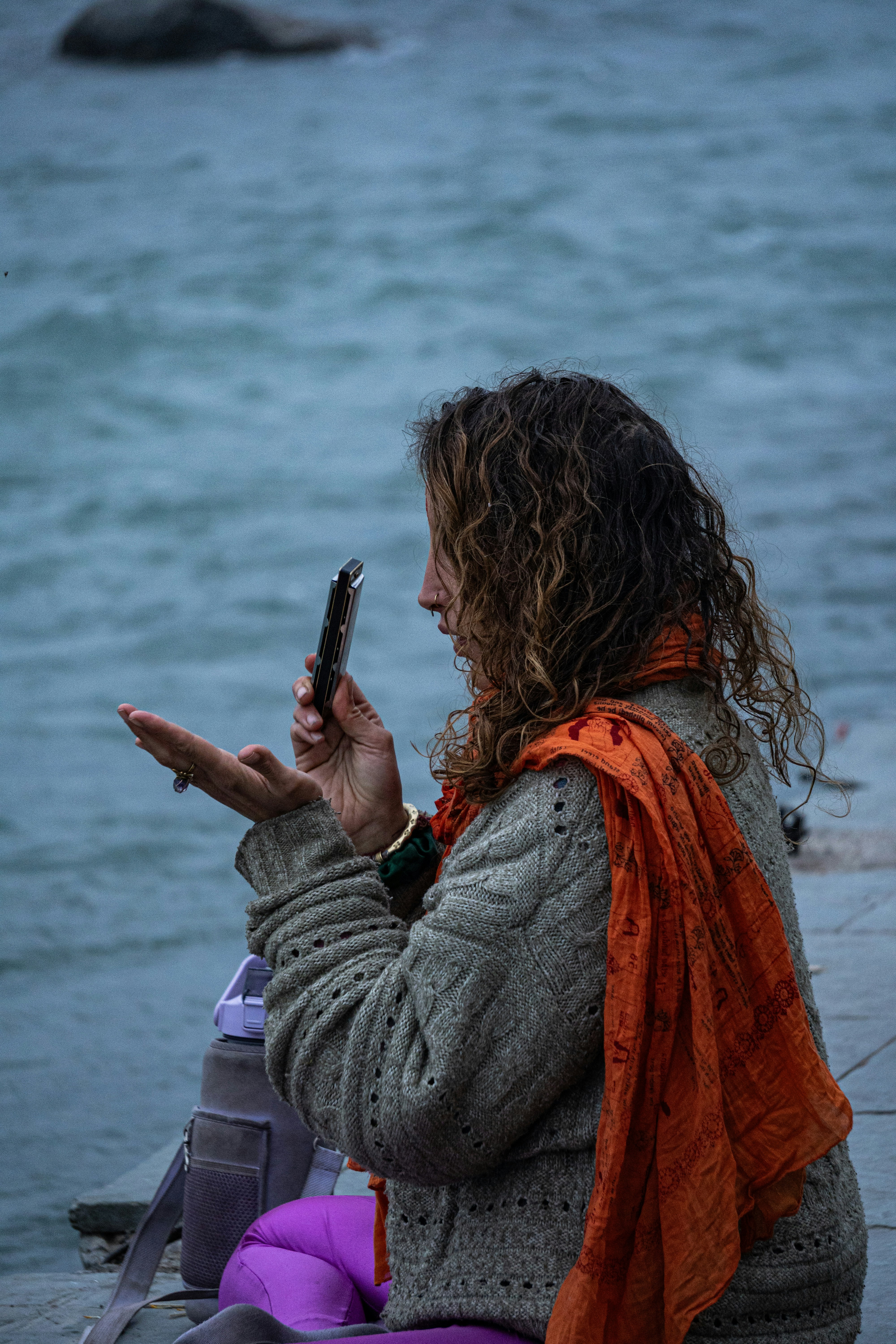 Frau mit lockigen Haaren macht ein Foto mit ihrem Handy.