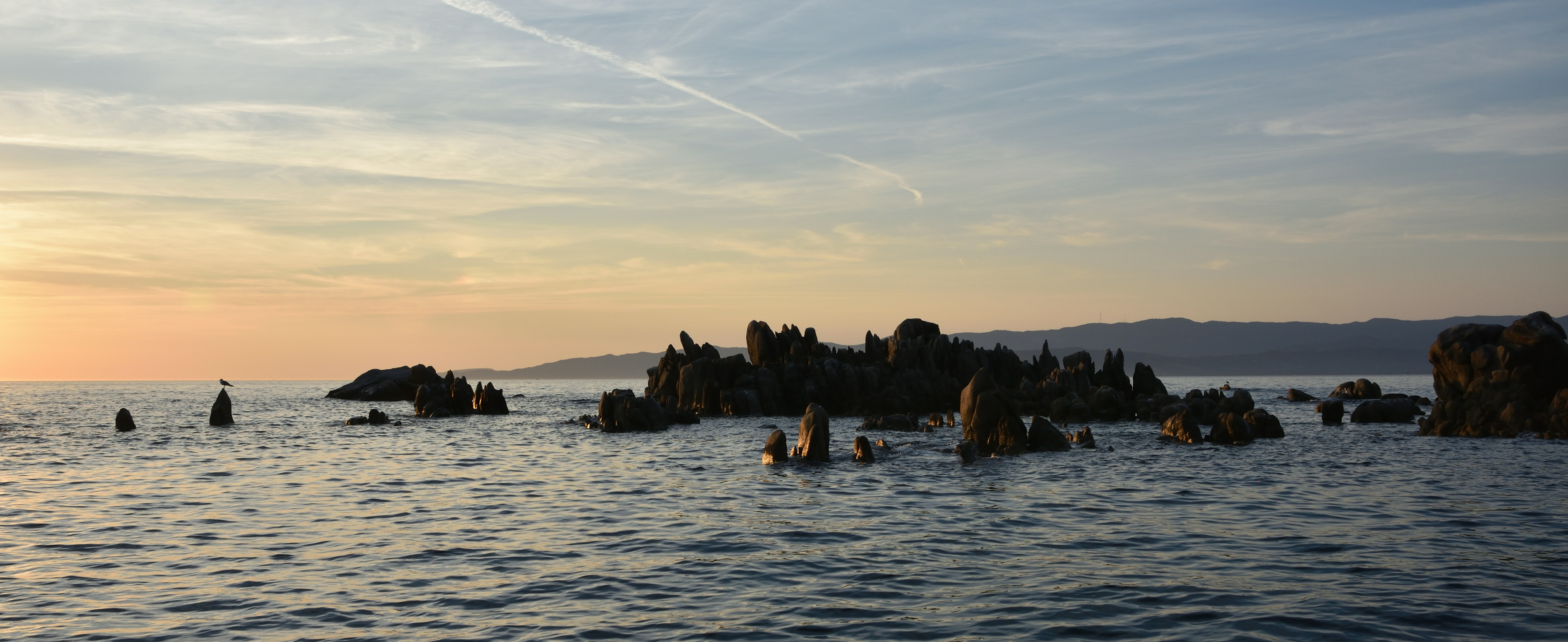 夕暮れ時の海に浮かぶ岩の露頭