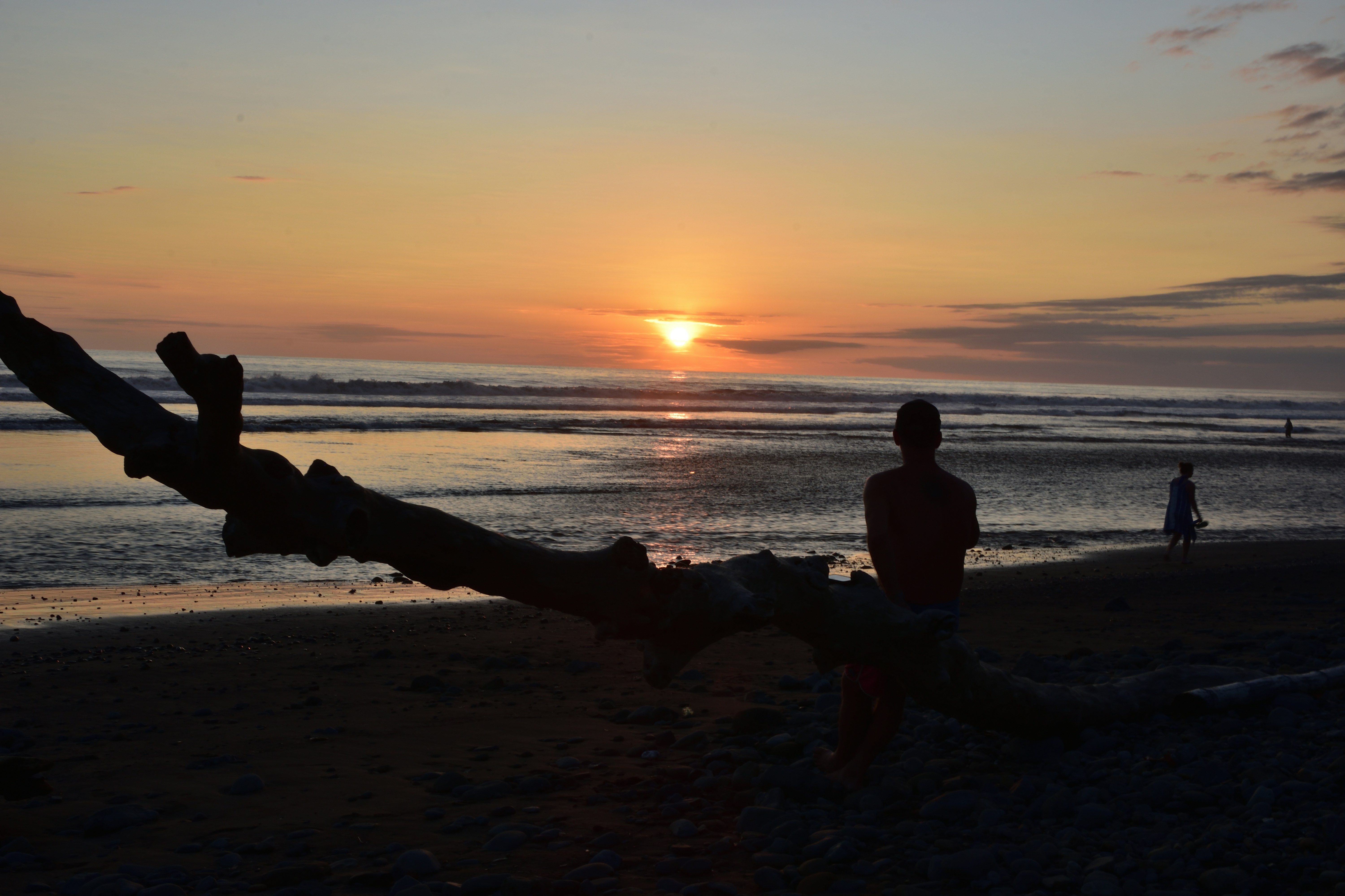ビーチで夕日を見ている人のシルエット。