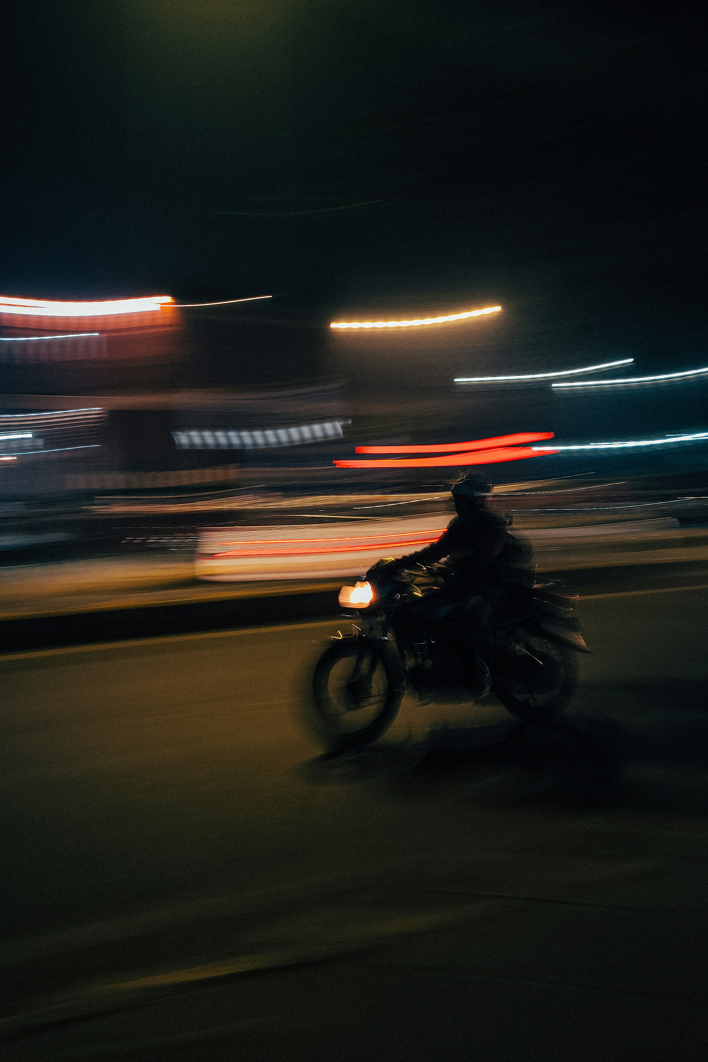 Motorcyclist speeding through city lights at night