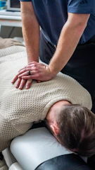 Chiropractor adjusting patient's upper back and neck.