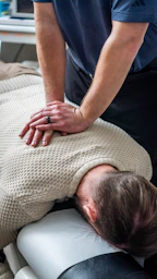 Chiropractor adjusting patient's upper back and neck.