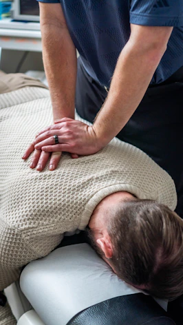 Chiropractor adjusting patient's upper back and neck.