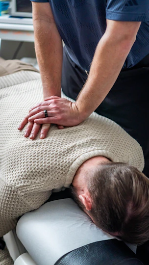 Chiropractor adjusting patient's upper back and neck.