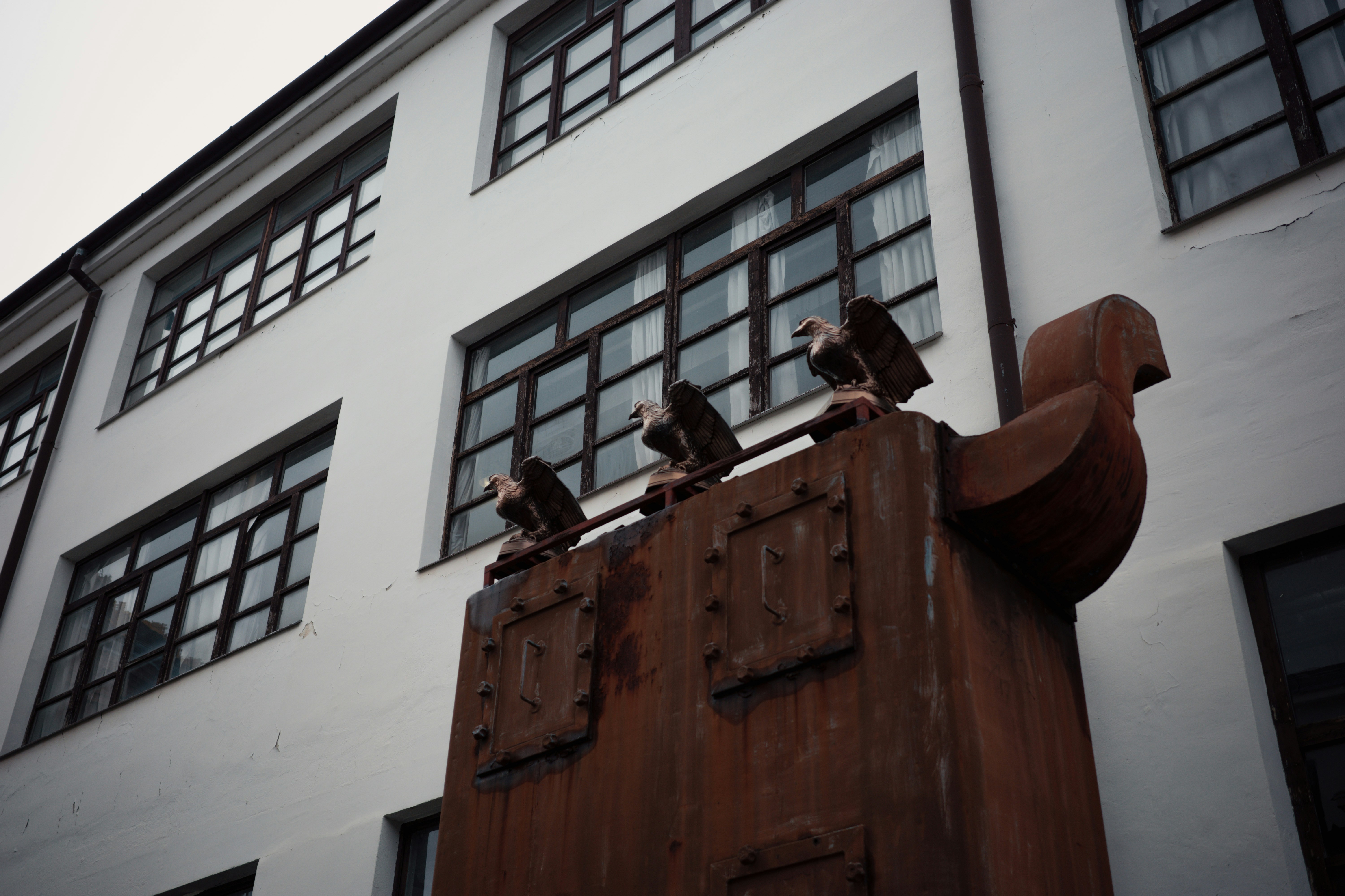 Three eagle statues on a rusty structure.