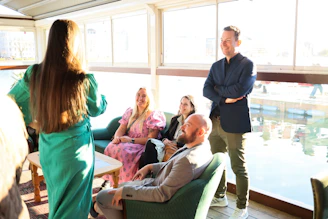 Group of people talking indoors near a window.