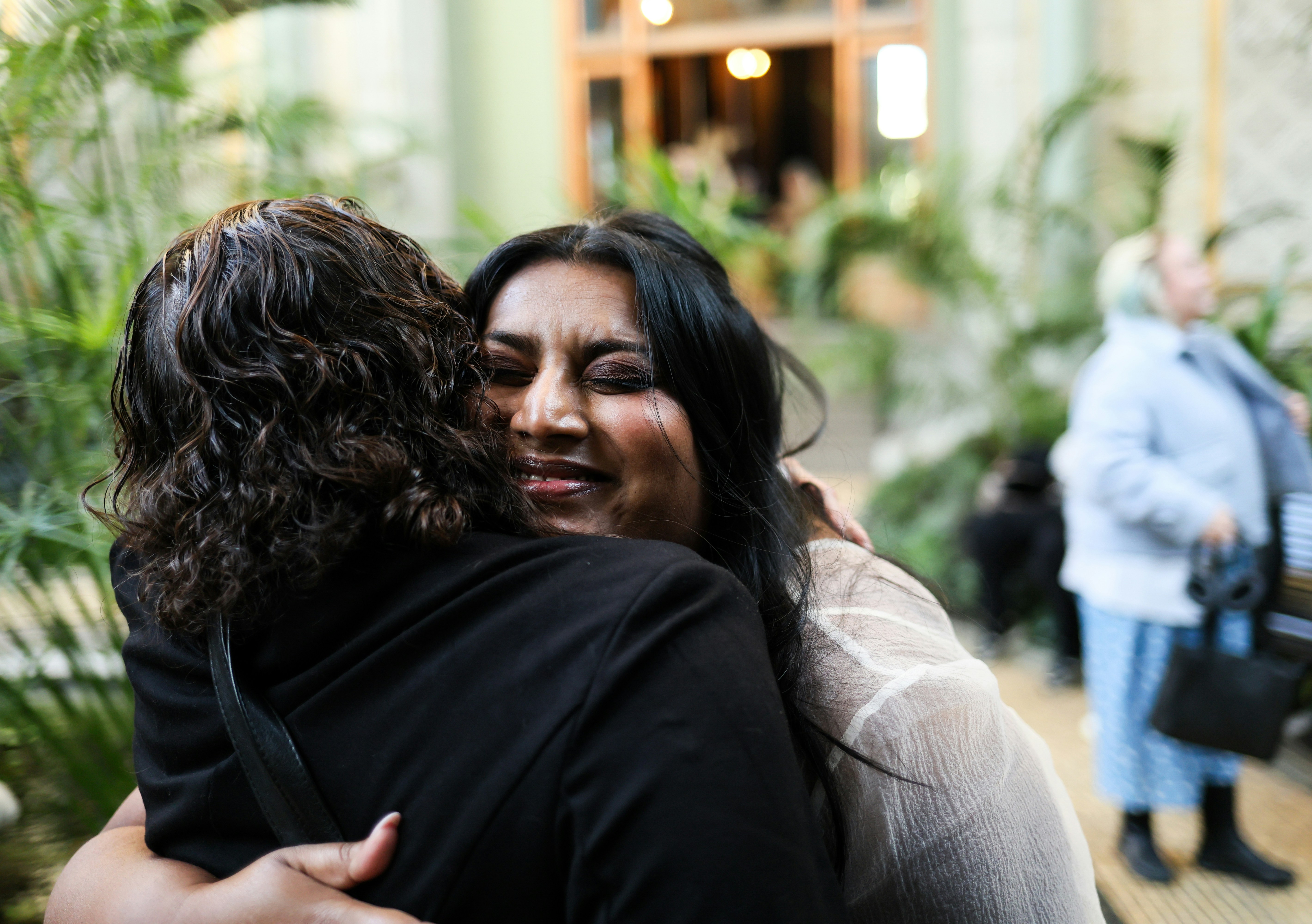 Two women embrace warmly in an outdoor setting.