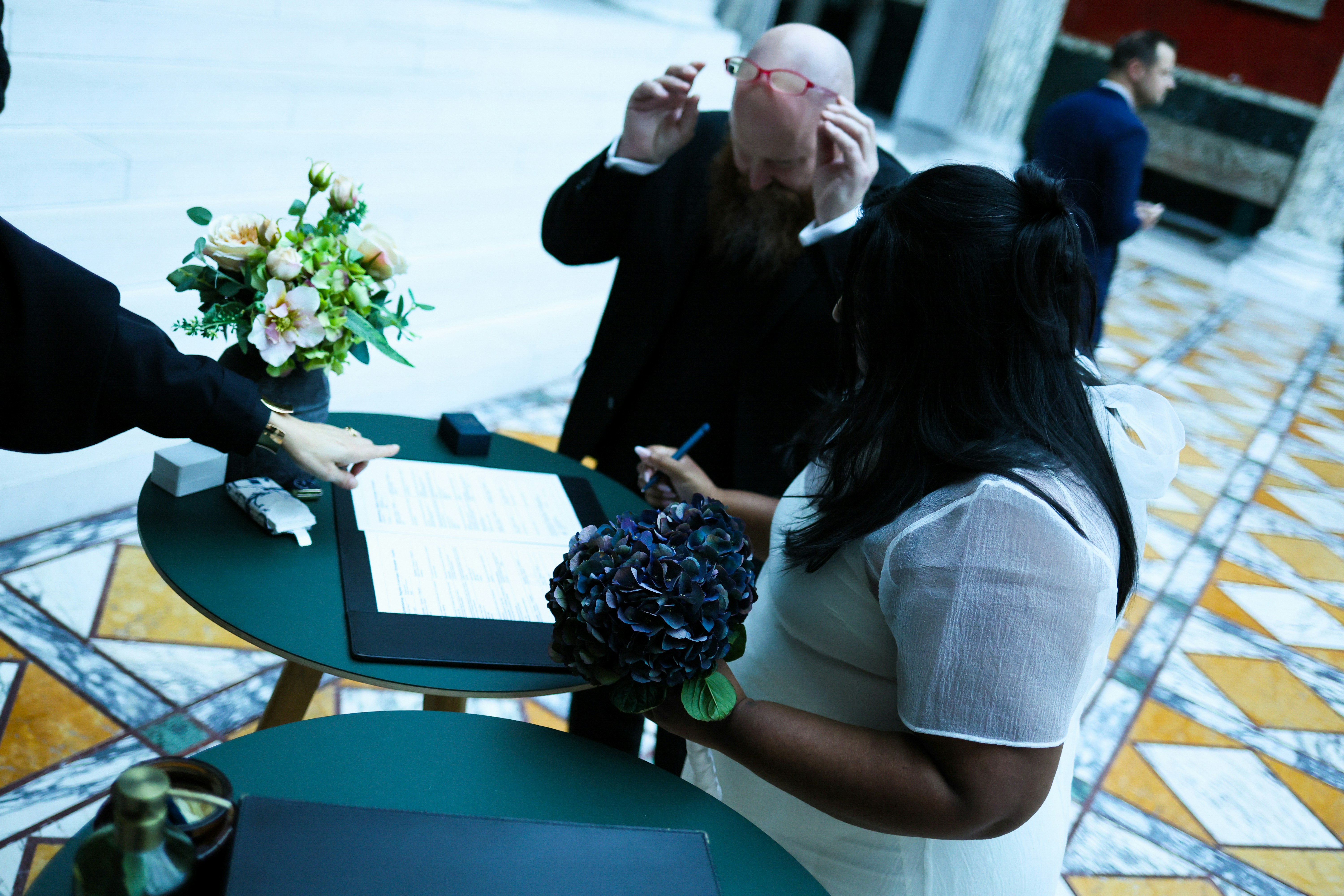 Couple signing marriage certificate with officiant present
