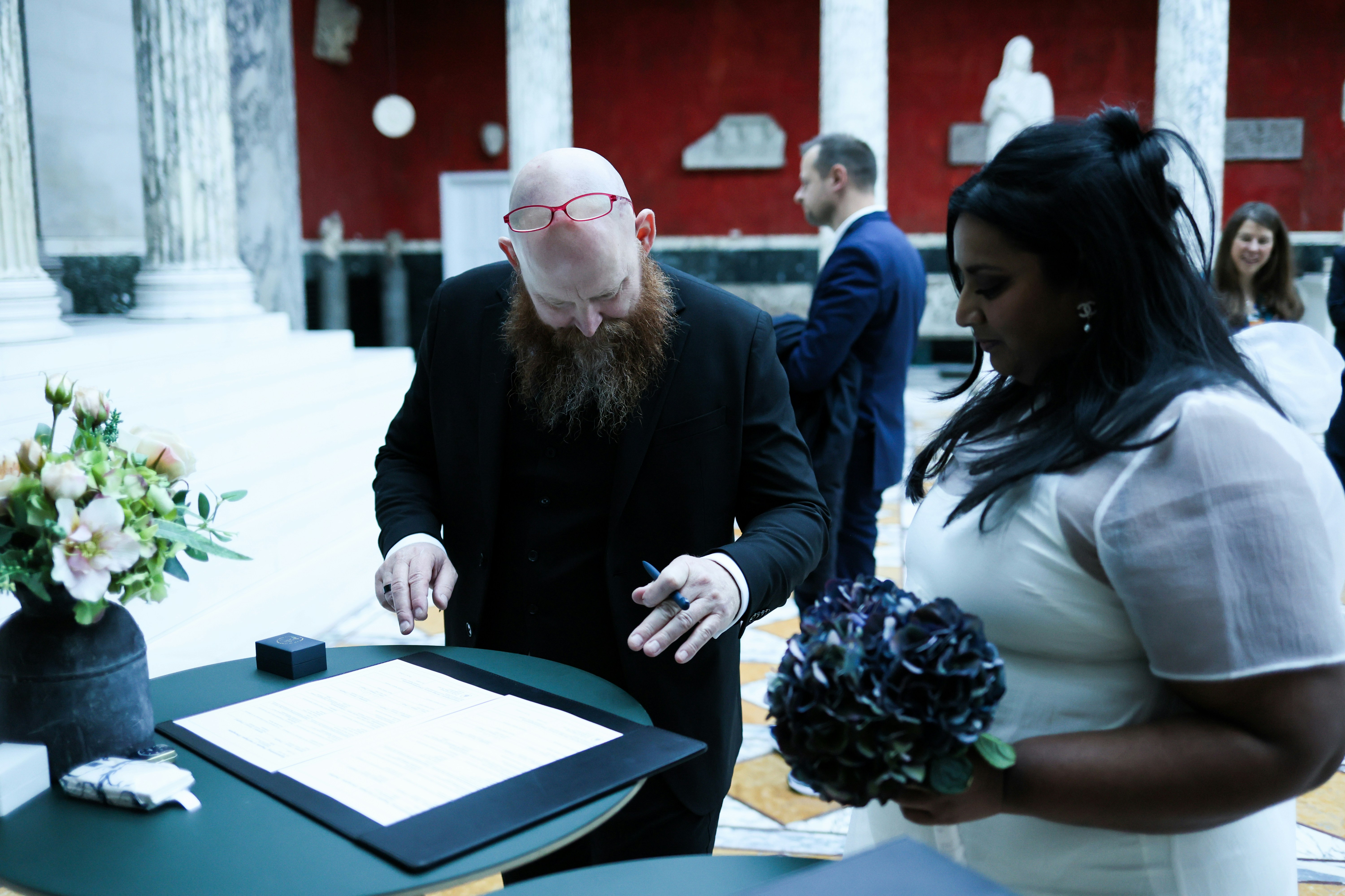 Couple signing wedding papers with guests watching