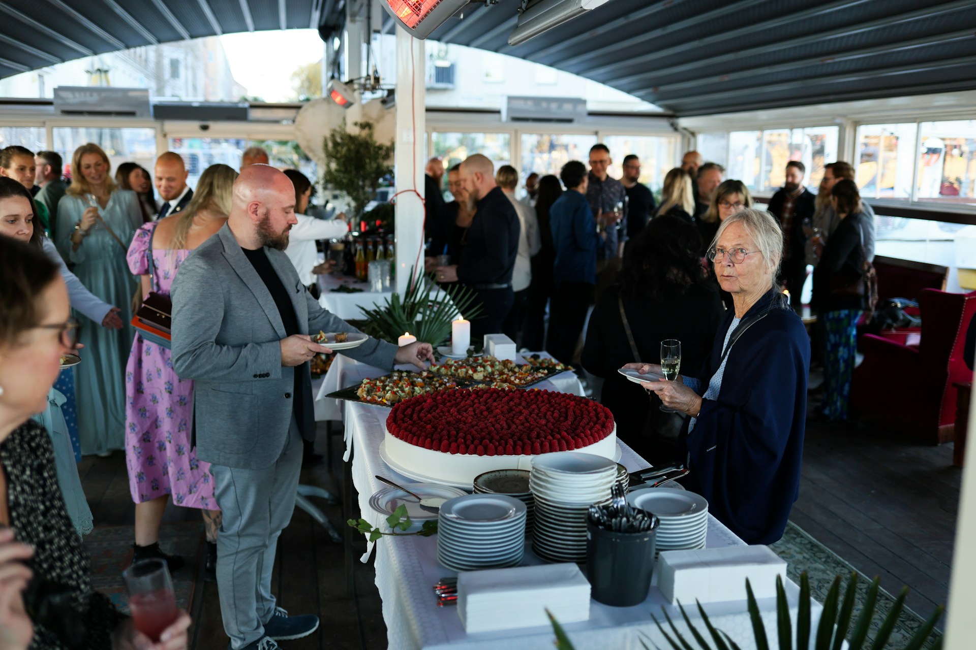 People gathered around a dessert buffet with a large cake.