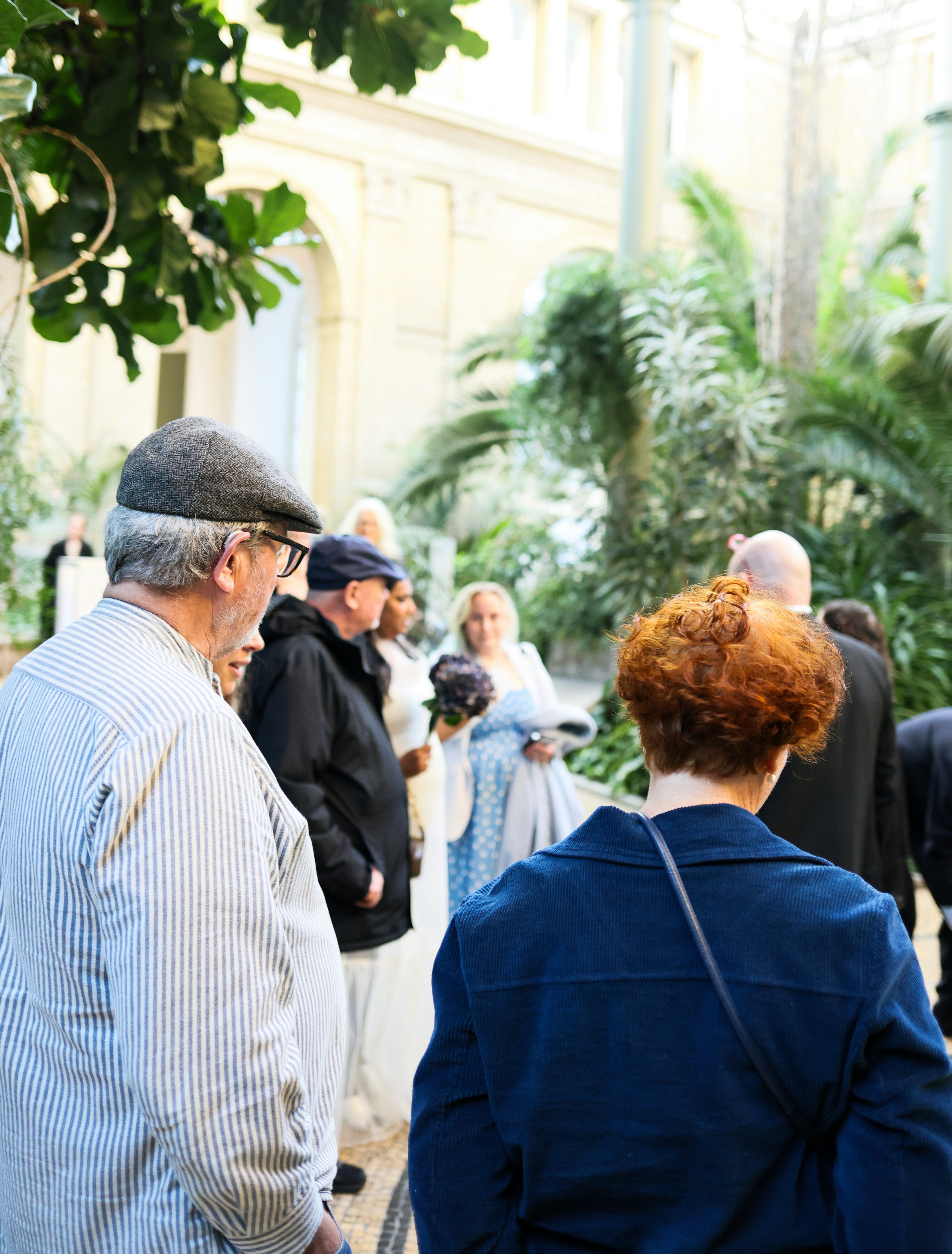 People gathered in a sunlit atrium with lush plants.
