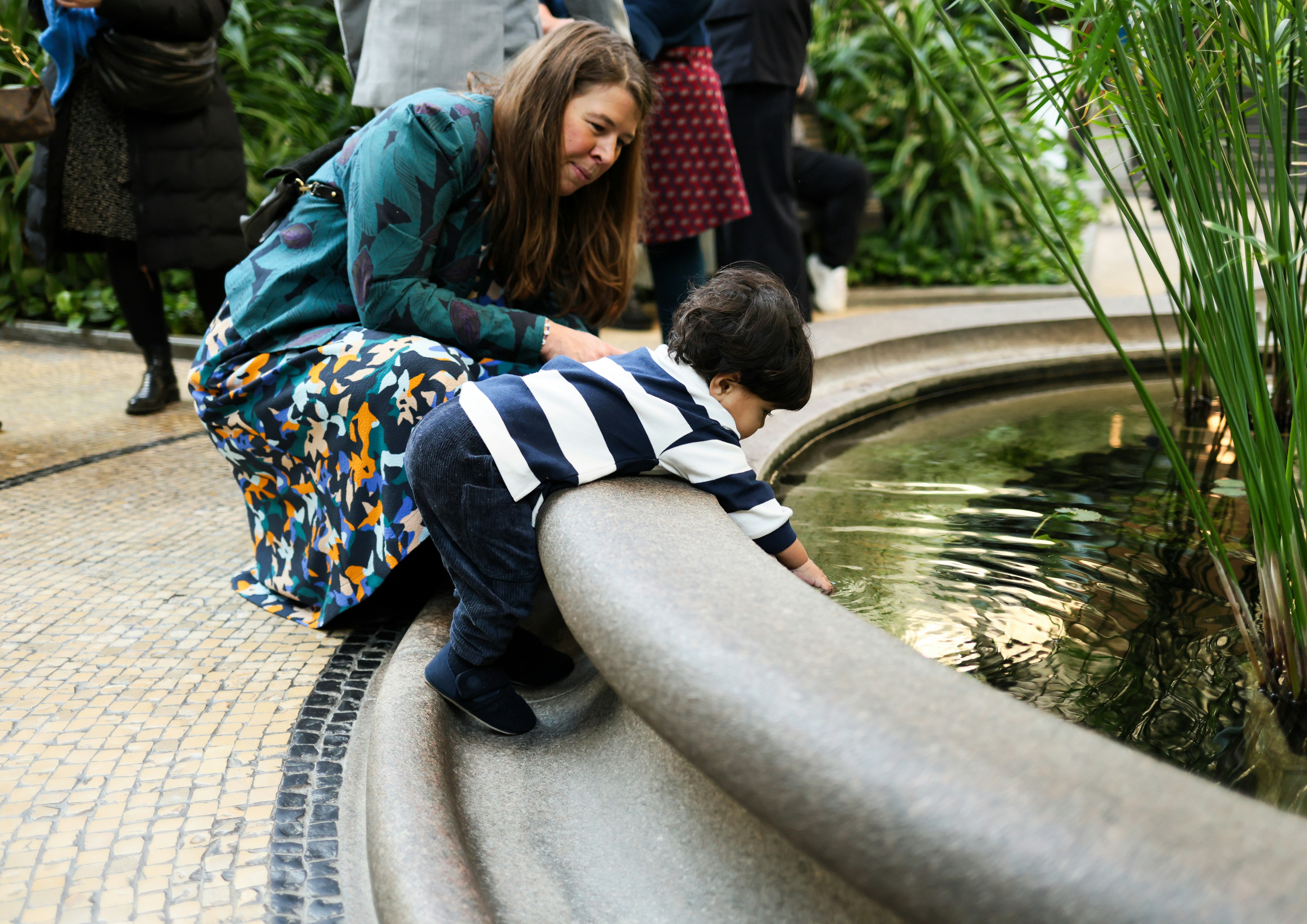 Woman and child looking at water in fountain