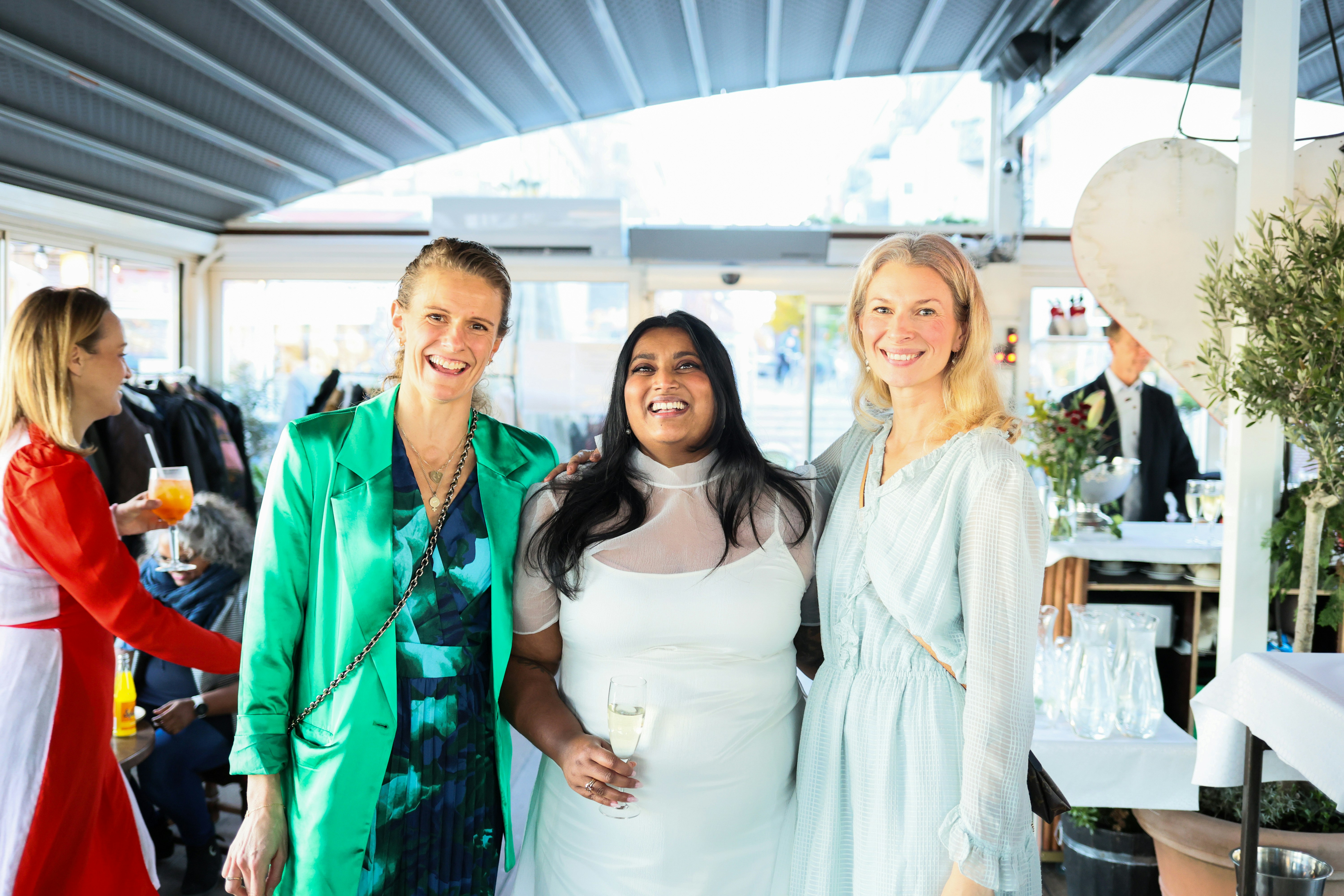 Three women smiling at a celebratory event