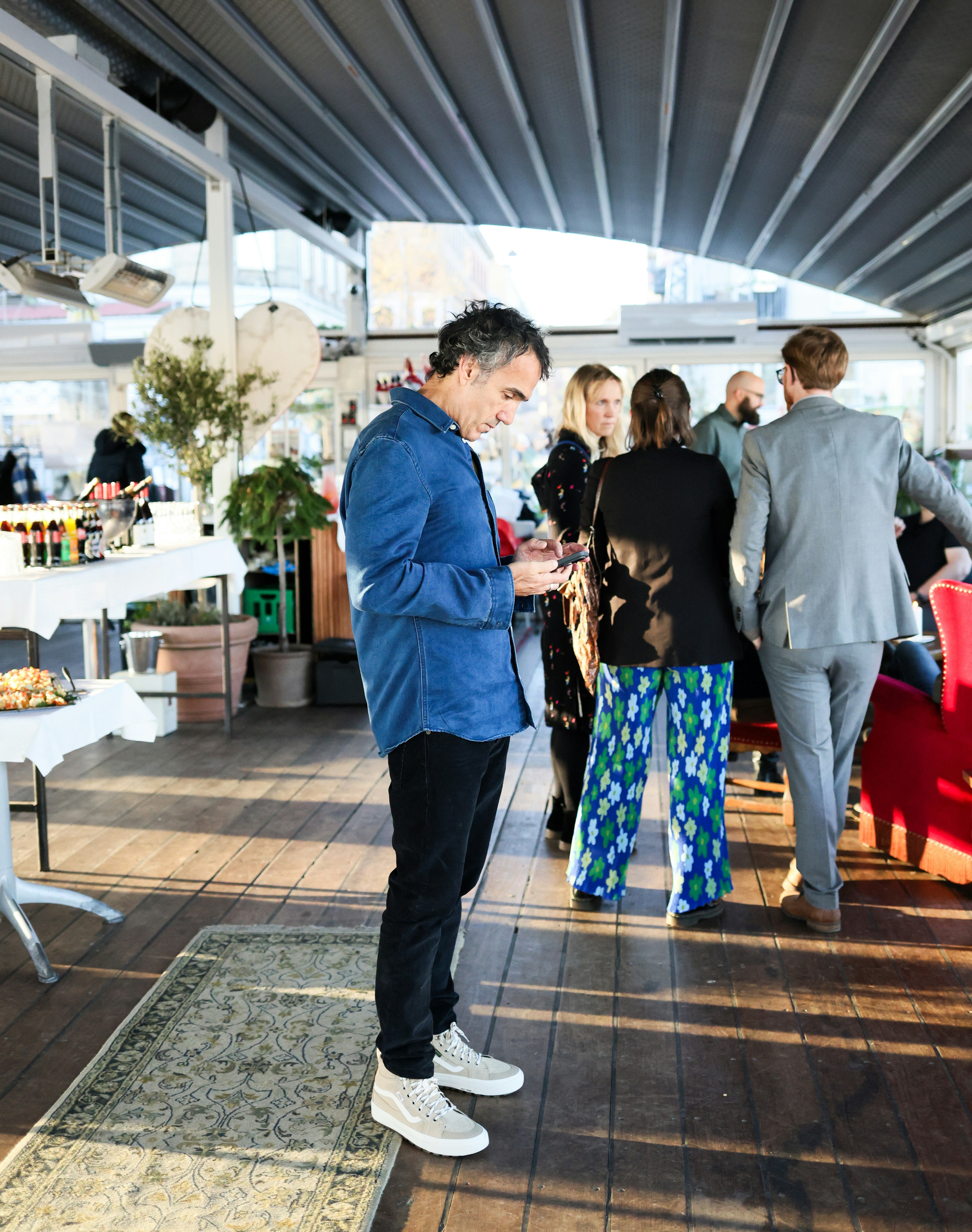 People mingling at an outdoor event with tables and seating.