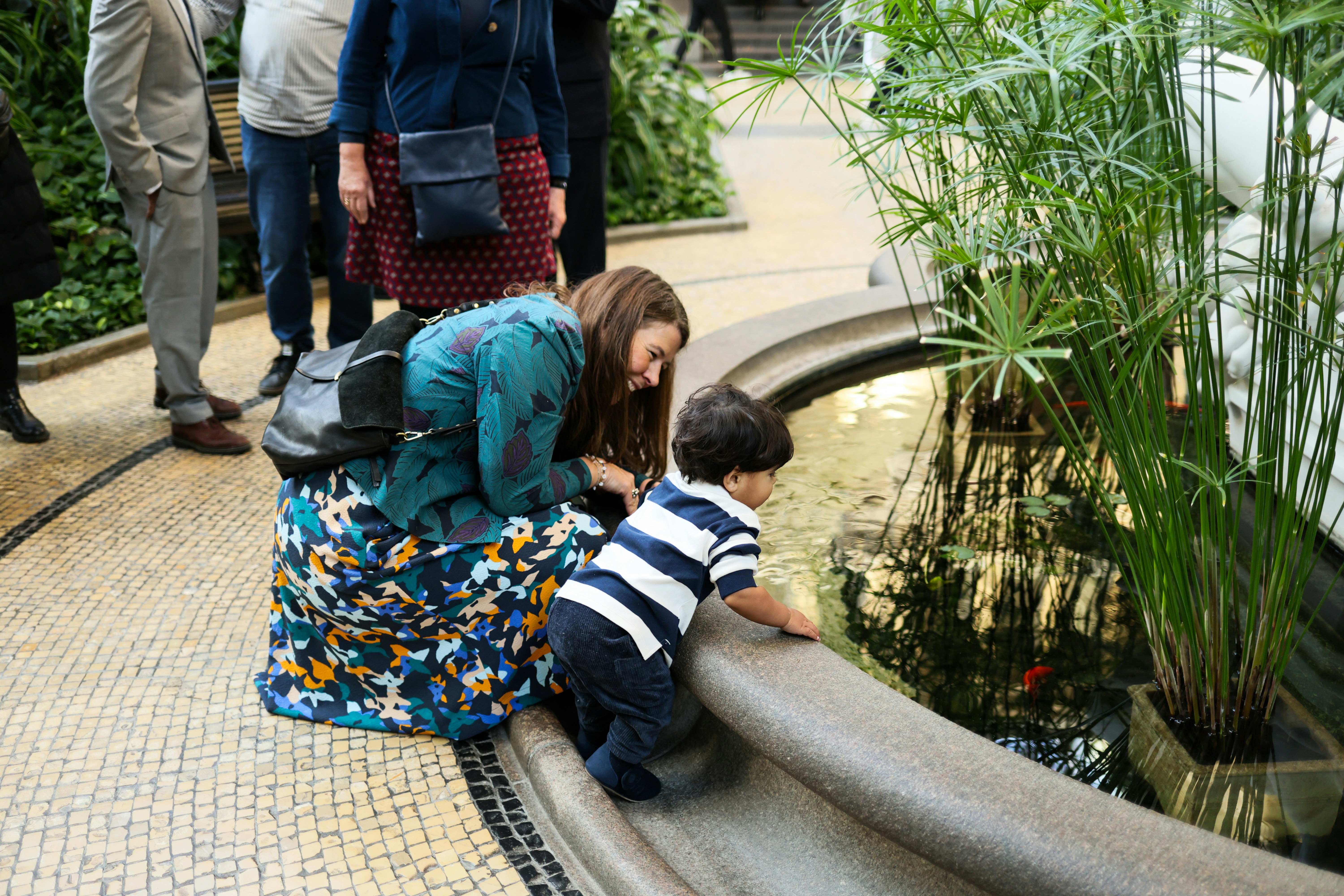 Woman and child look at fish in fountain