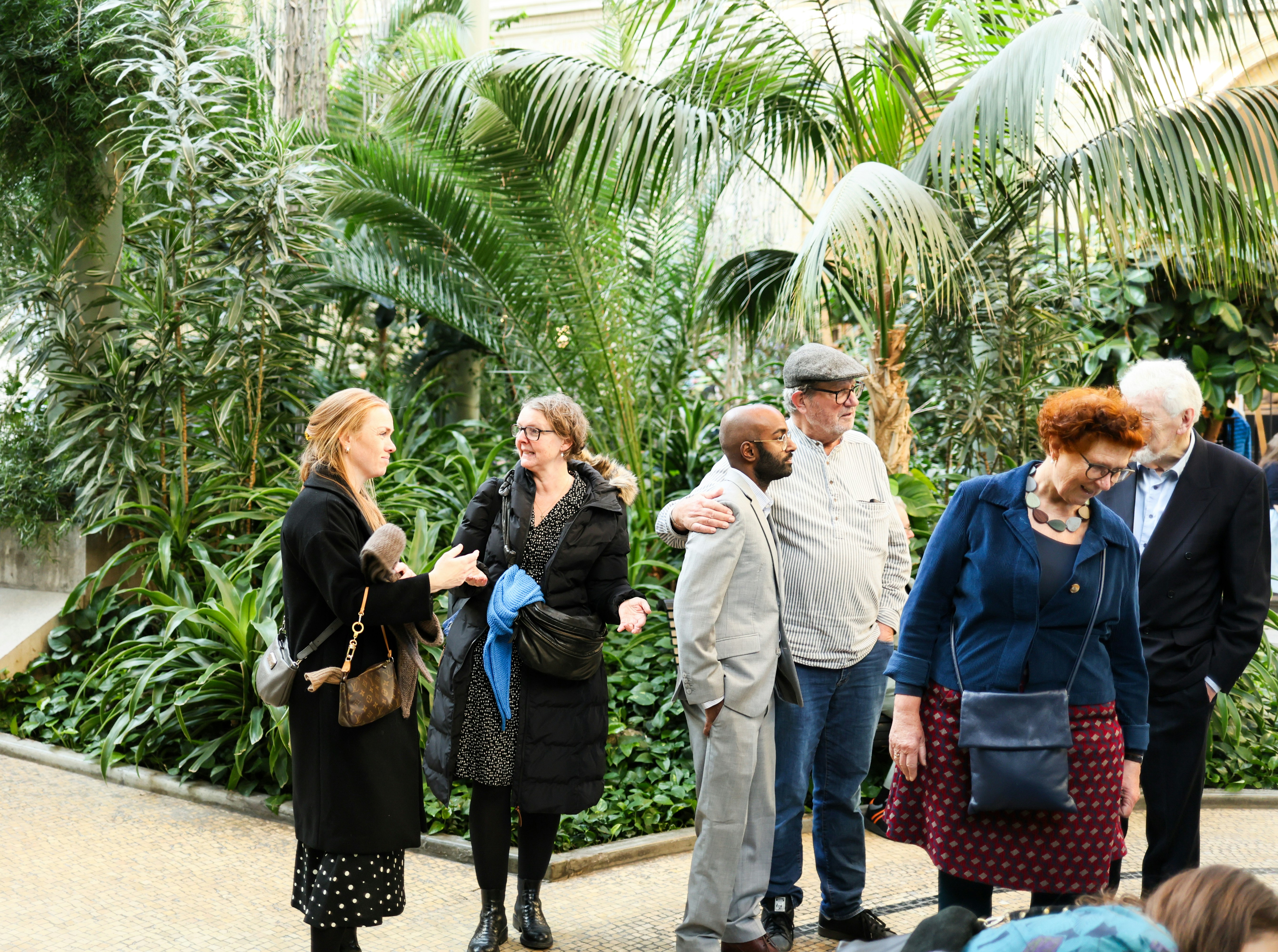People gathered in a lush botanical garden with tropical plants.
