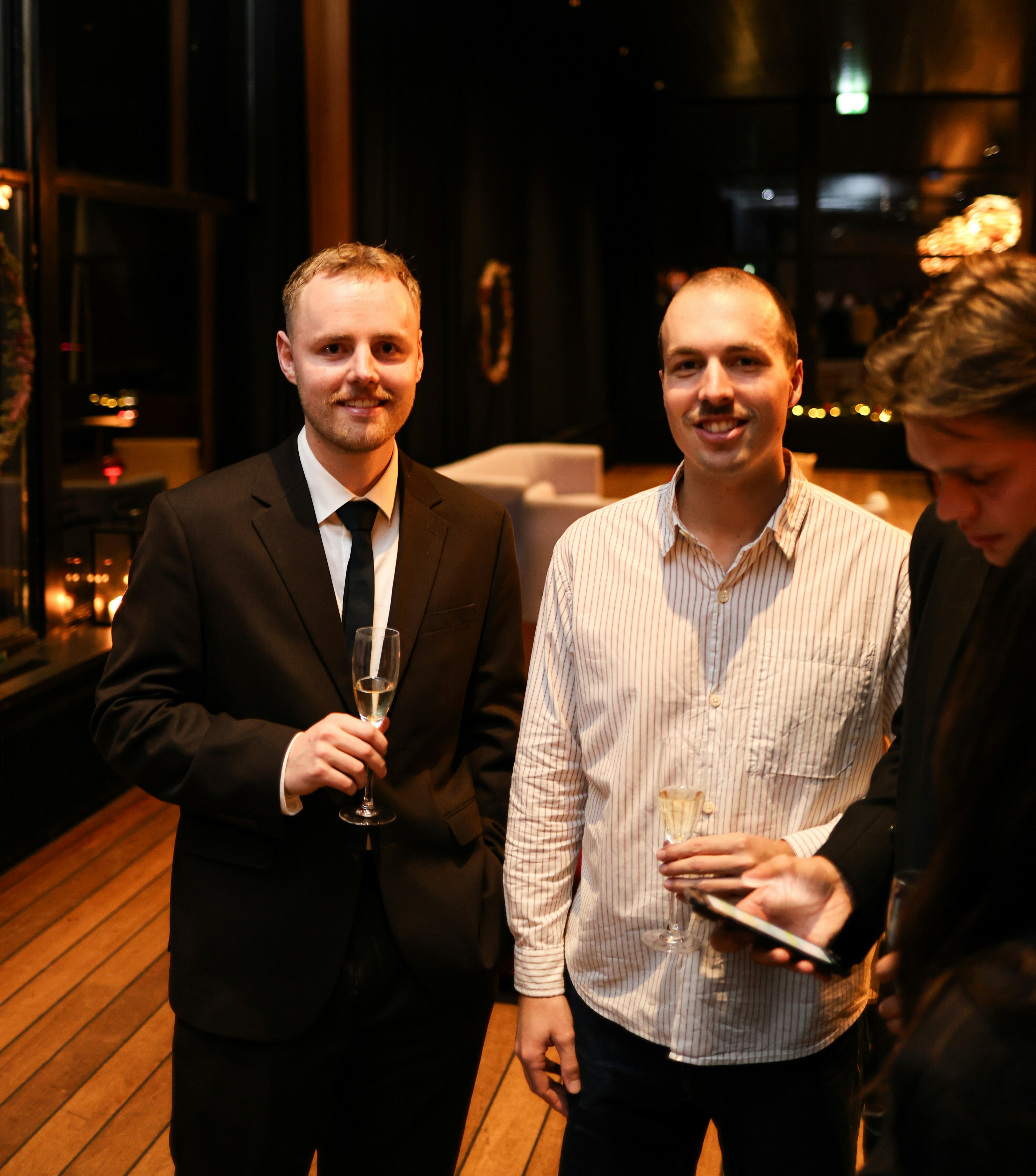 Two men in formal attire holding drinks