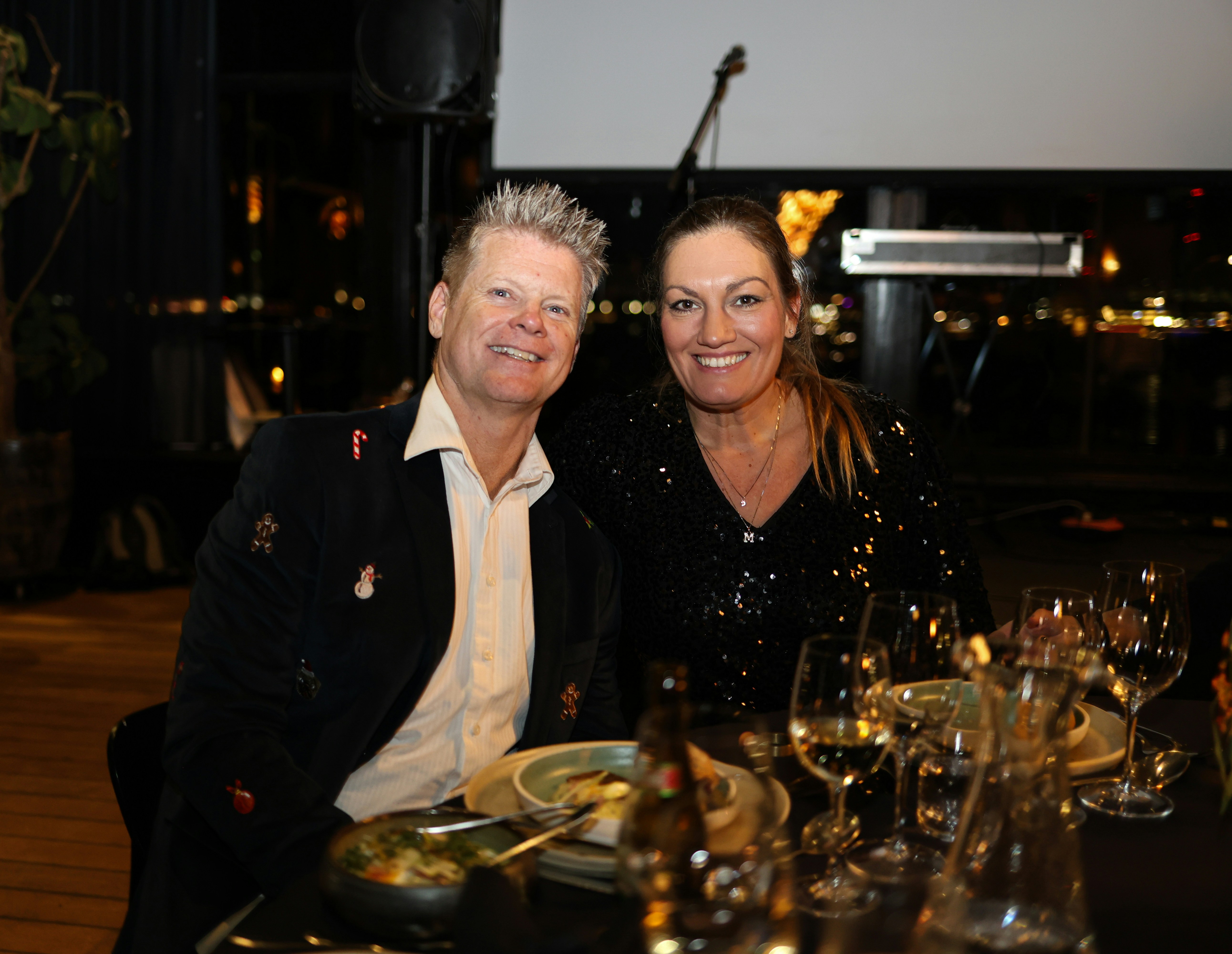 Ein Mann und eine Frau lächeln bei einem formellen Abendessen.