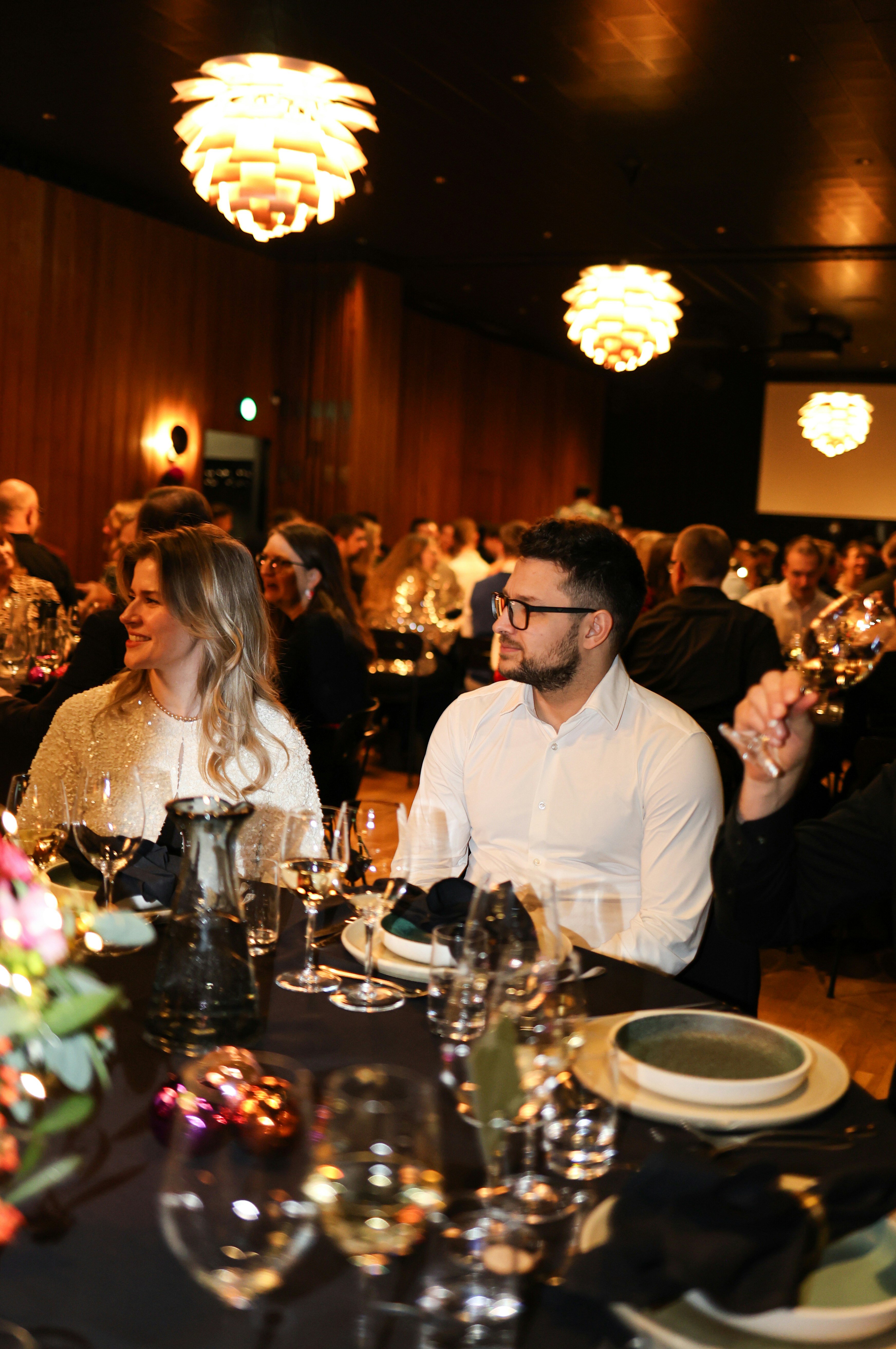 People seated at a formal dinner event with elegant lighting.