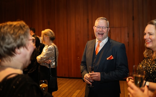 Man in suit laughing with friends at a party