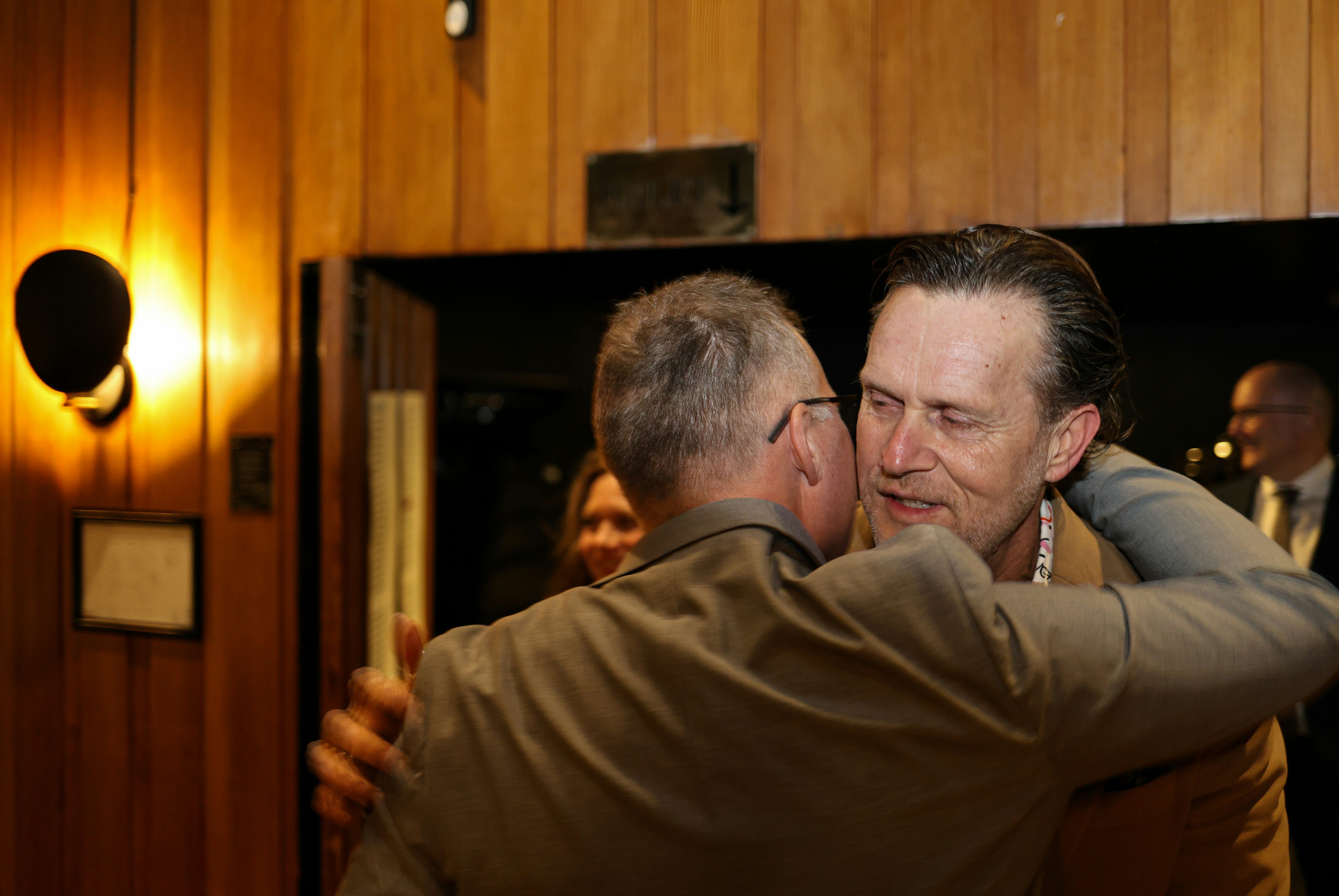 Zwei Männer umarmten sich herzlich in einem schwach beleuchteten Raum.
