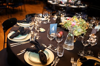 Elegant table setting with floral centerpiece and wine glasses.